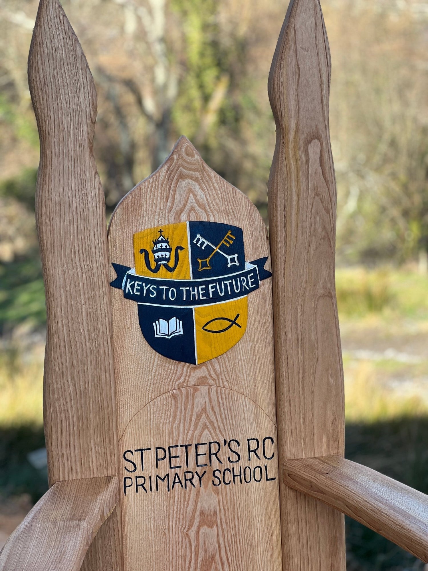 Custom oak storytelling chair featuring school logo and lettering, designed for outdoor learning spaces