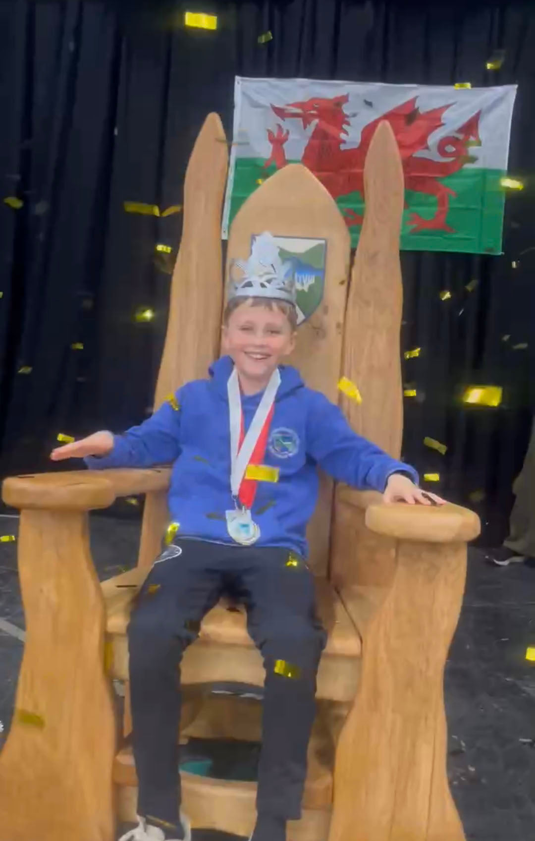 Child sitting in handcrafted oak storytelling chair at Ysgol Rhaeadr Gwy school Eisteddfod