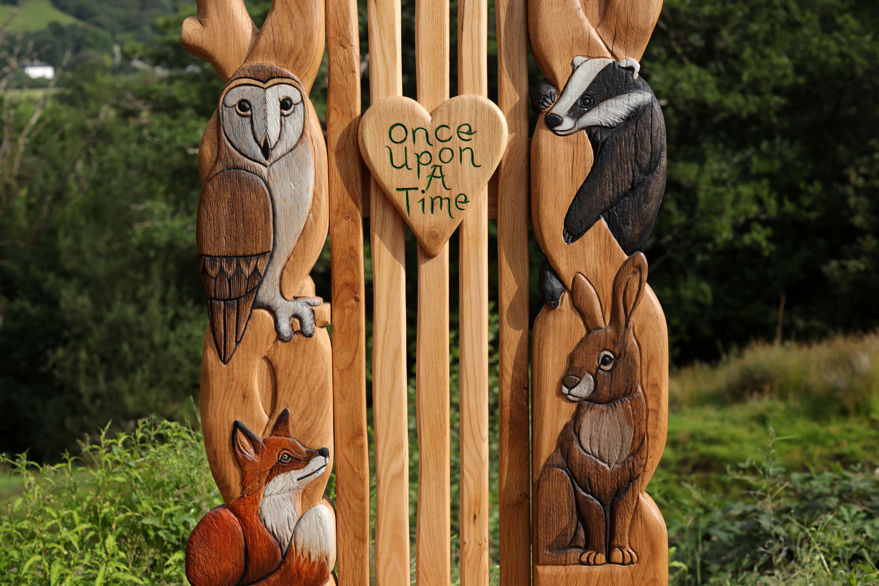 Wooden spoons with animal carvings and a heart-shaped sign reading 'Once Upon A Time' against a natural background.