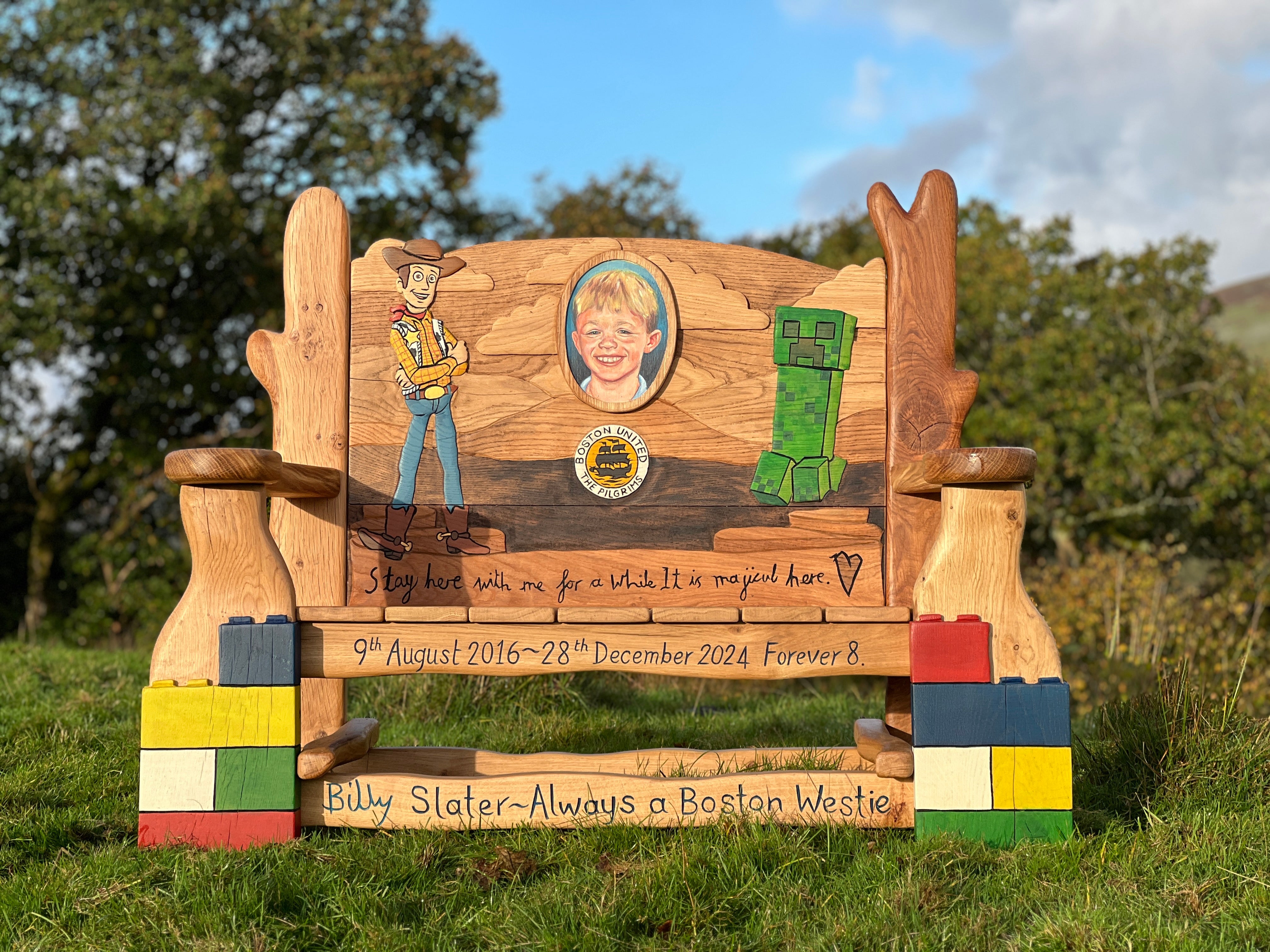 Wooden bench with engraved images and text in an outdoor setting