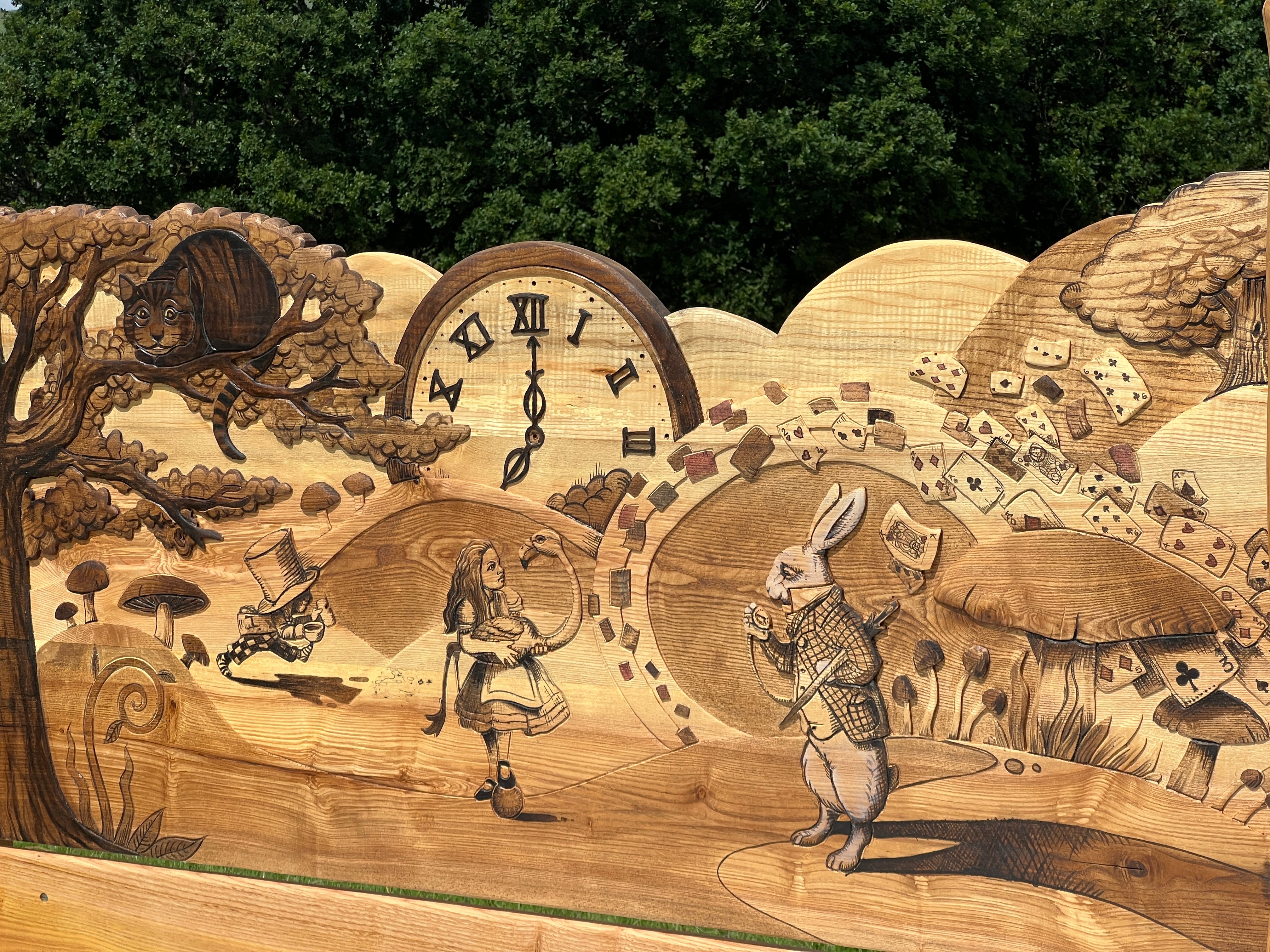 Detailed carved and stained woodwork of Alice, White Rabbit and Cheshire Cat on wooden bed