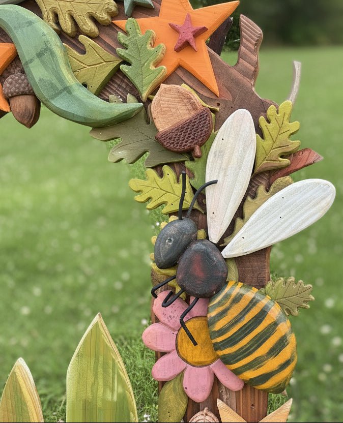 Decorative arch with leaves, acorns, and a bee on a metal surface
