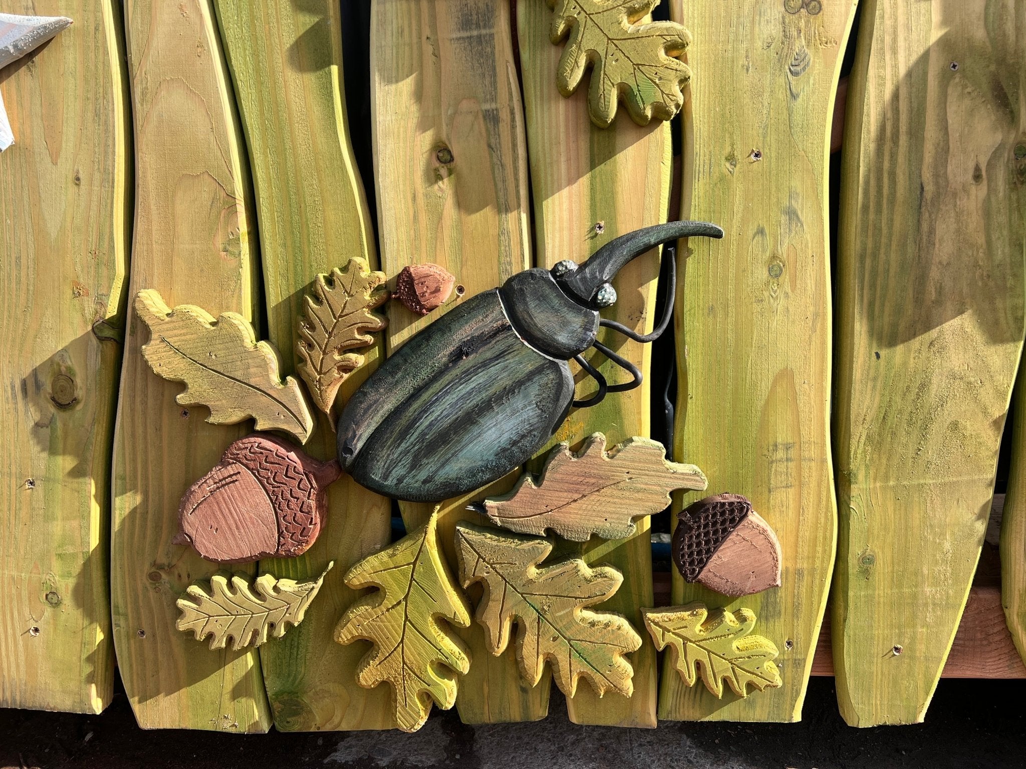 Wooden archway with a beetle and leaves on a wooden gate