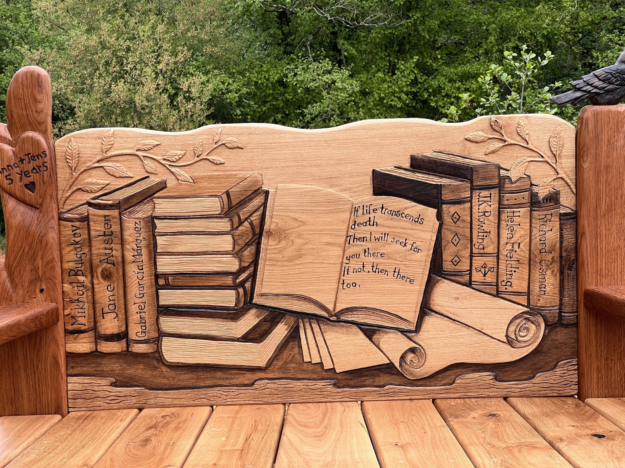 Close-up of the carved book spines and stacked books on the solid oak bench backrest