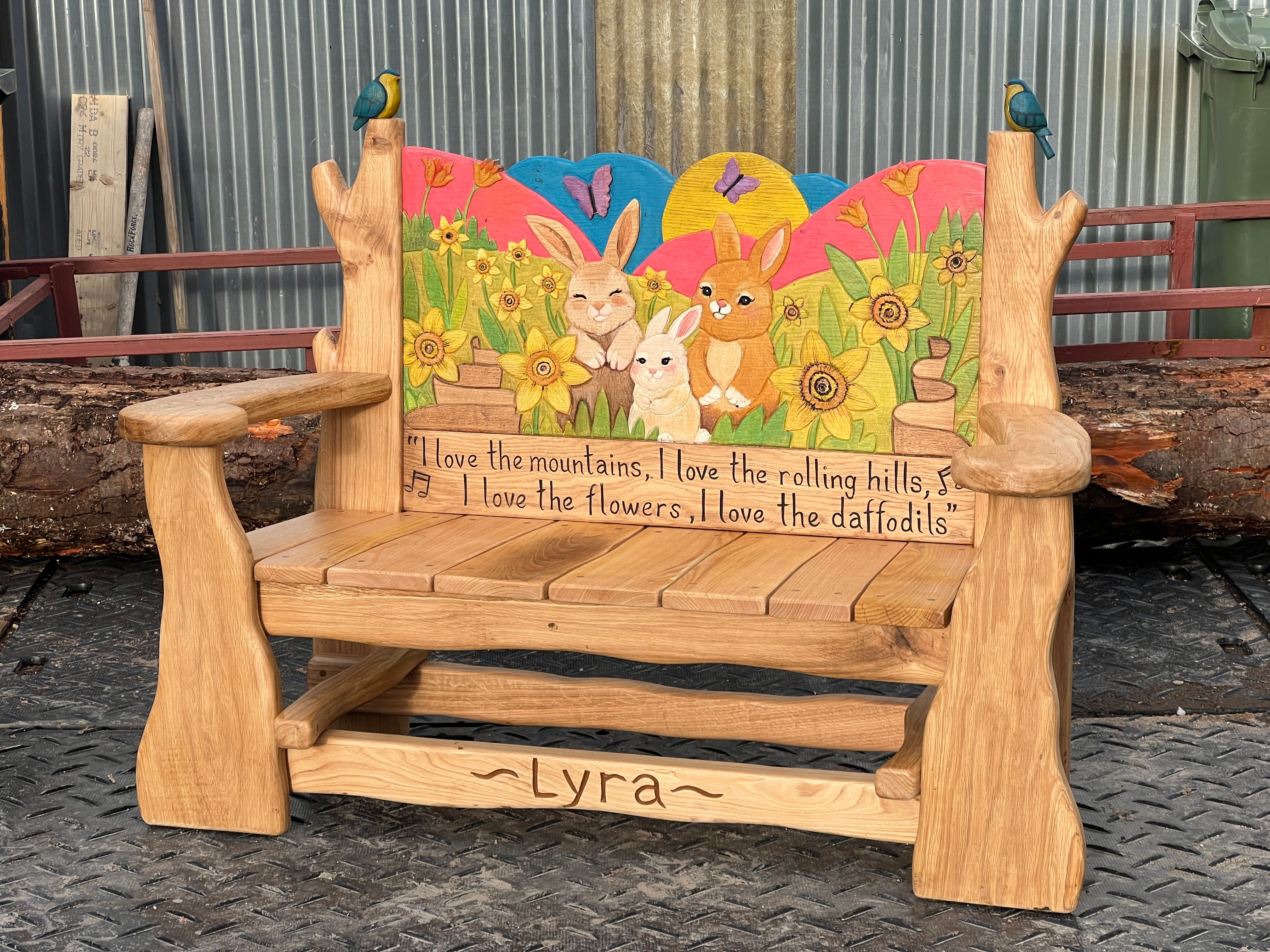 Side view of hand-carved oak memorial bench showing carved panels, natural wood grain and bespoke remembrance artwork