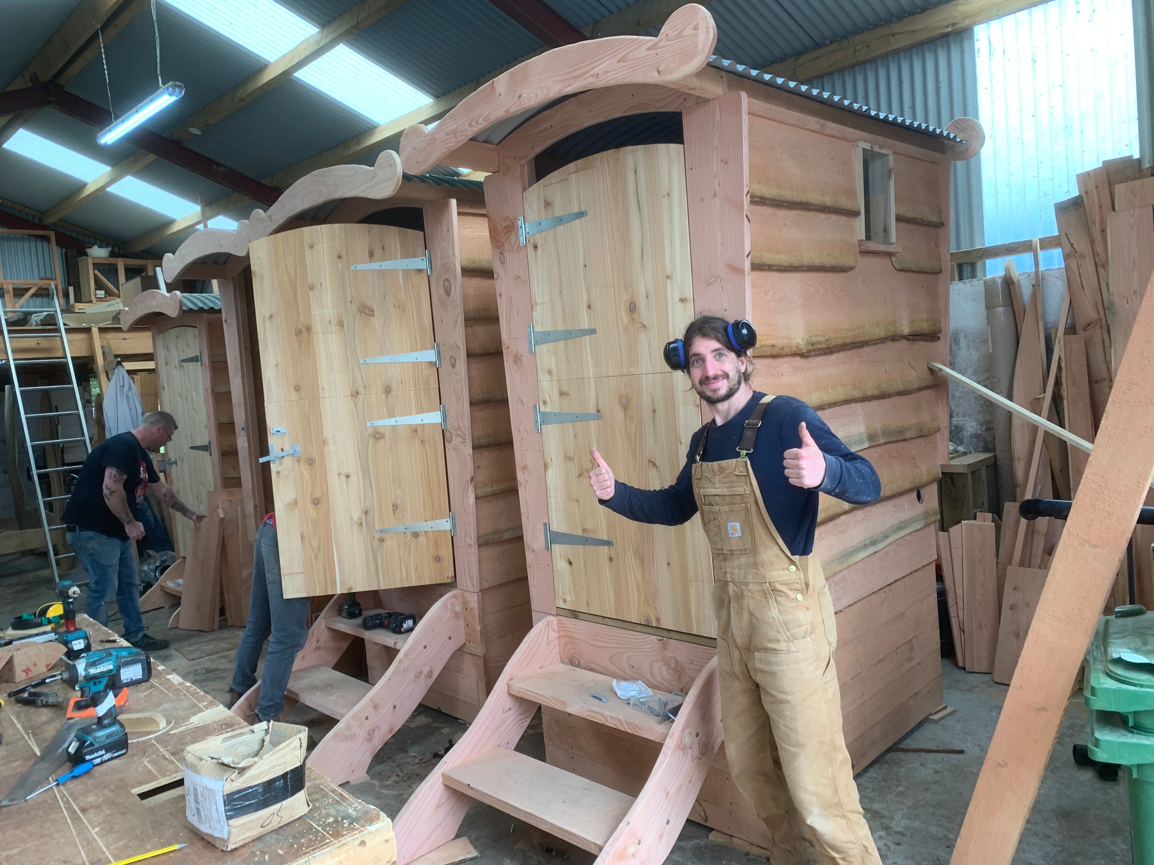 Two craftsmen building wooden compost toilets in the Free Range Designs workshop in Mid-Wales, showing handmade construction and attention to detail.