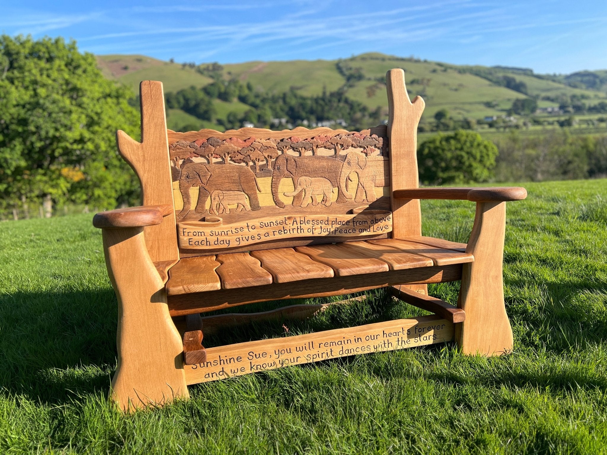 Side view of handcrafted oak memorial bench showing natural wooden contours and flowing armrests.