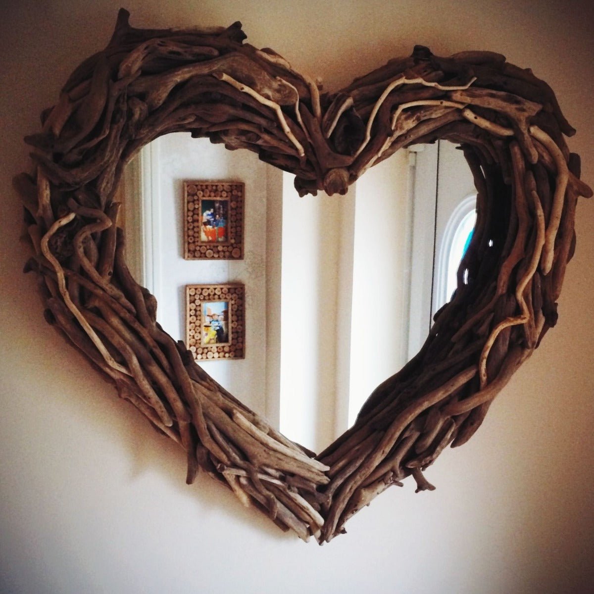 Heart mirror with driftwood frame on beige wall