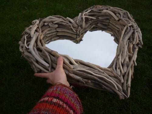 Hand holding heart-shaped driftwood mirror