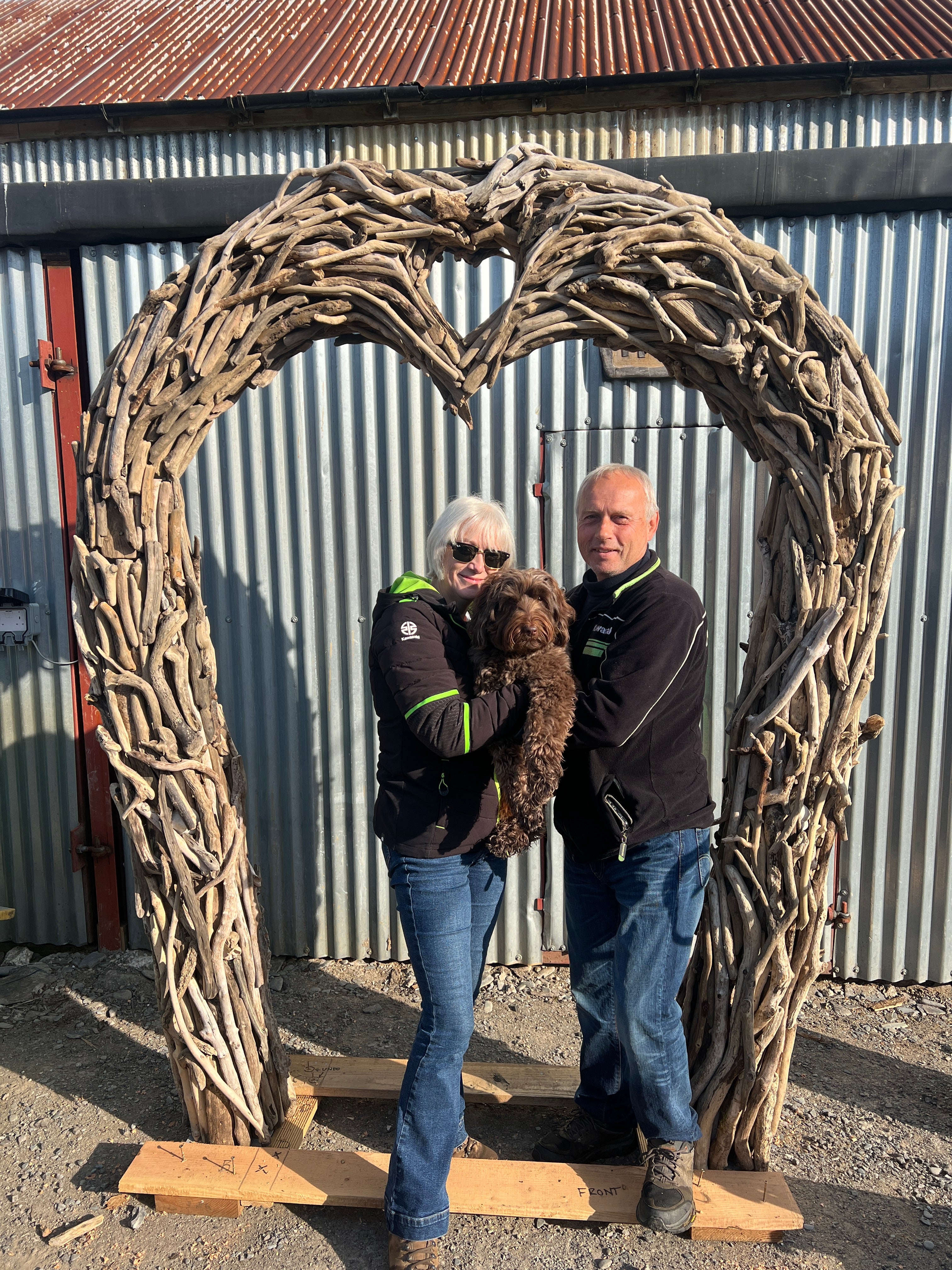 couple under a driftwood wedding arch