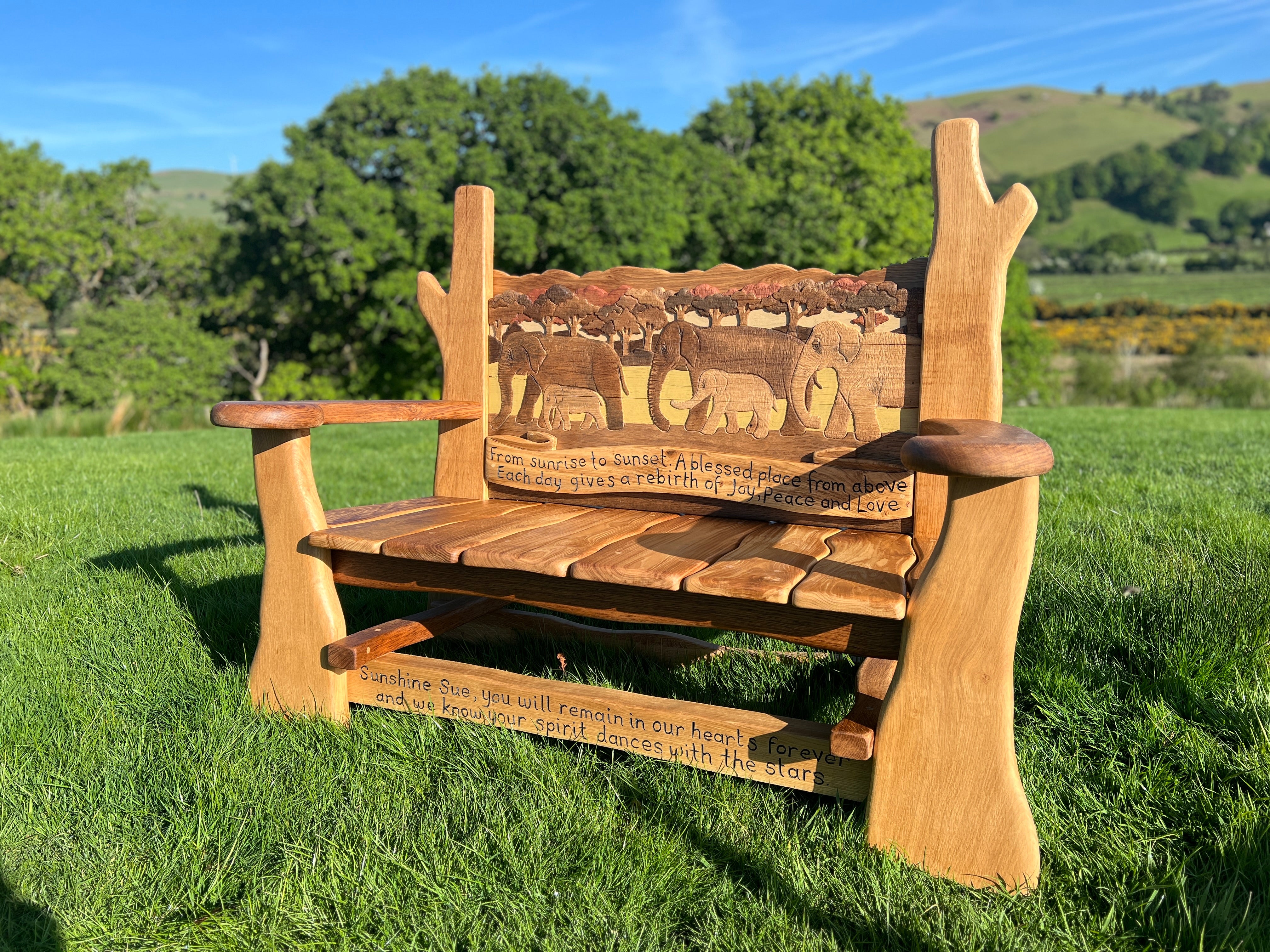 Side view of handcrafted oak memorial bench showing natural wooden contours and flowing armrests.