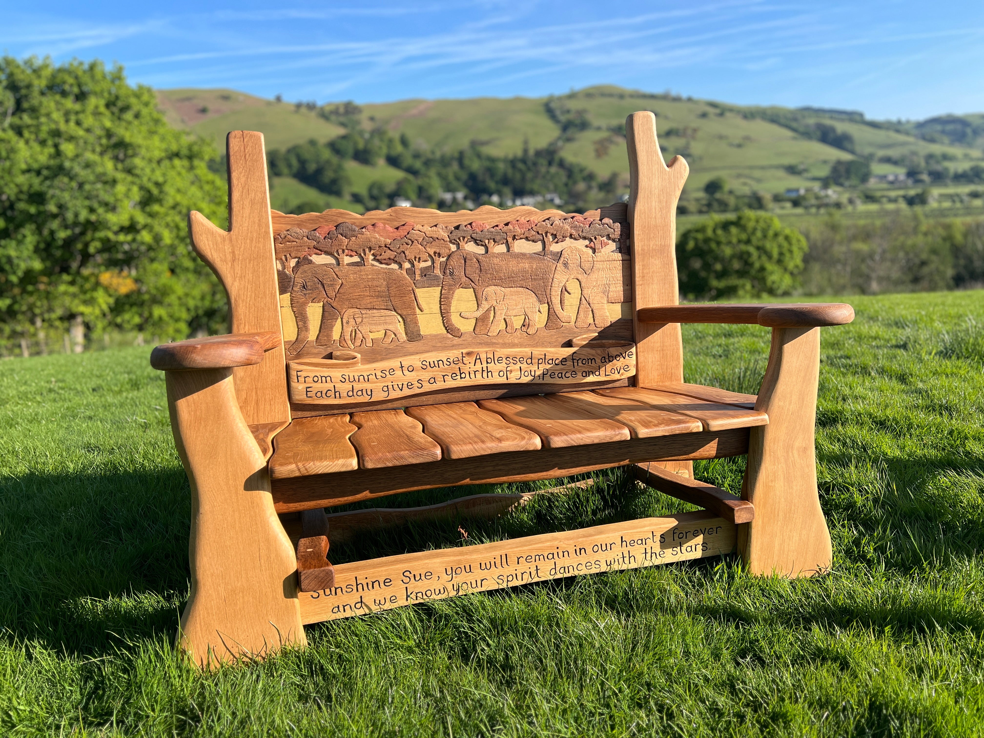 Side view of handcrafted oak memorial bench showing natural wooden contours and flowing armrests.