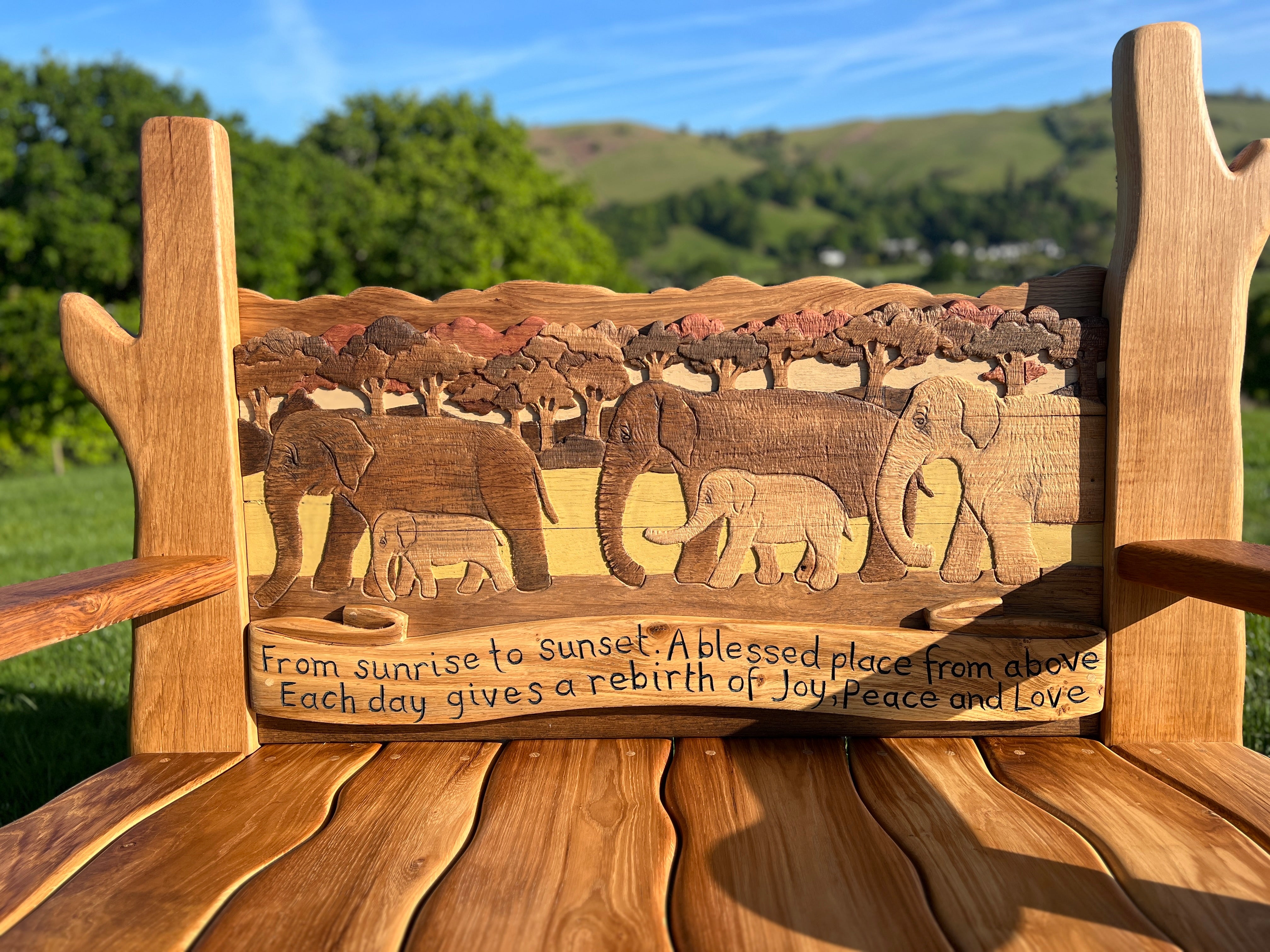 Close-up of elephant carving and engraved message on backrest of bespoke oak memorial bench.