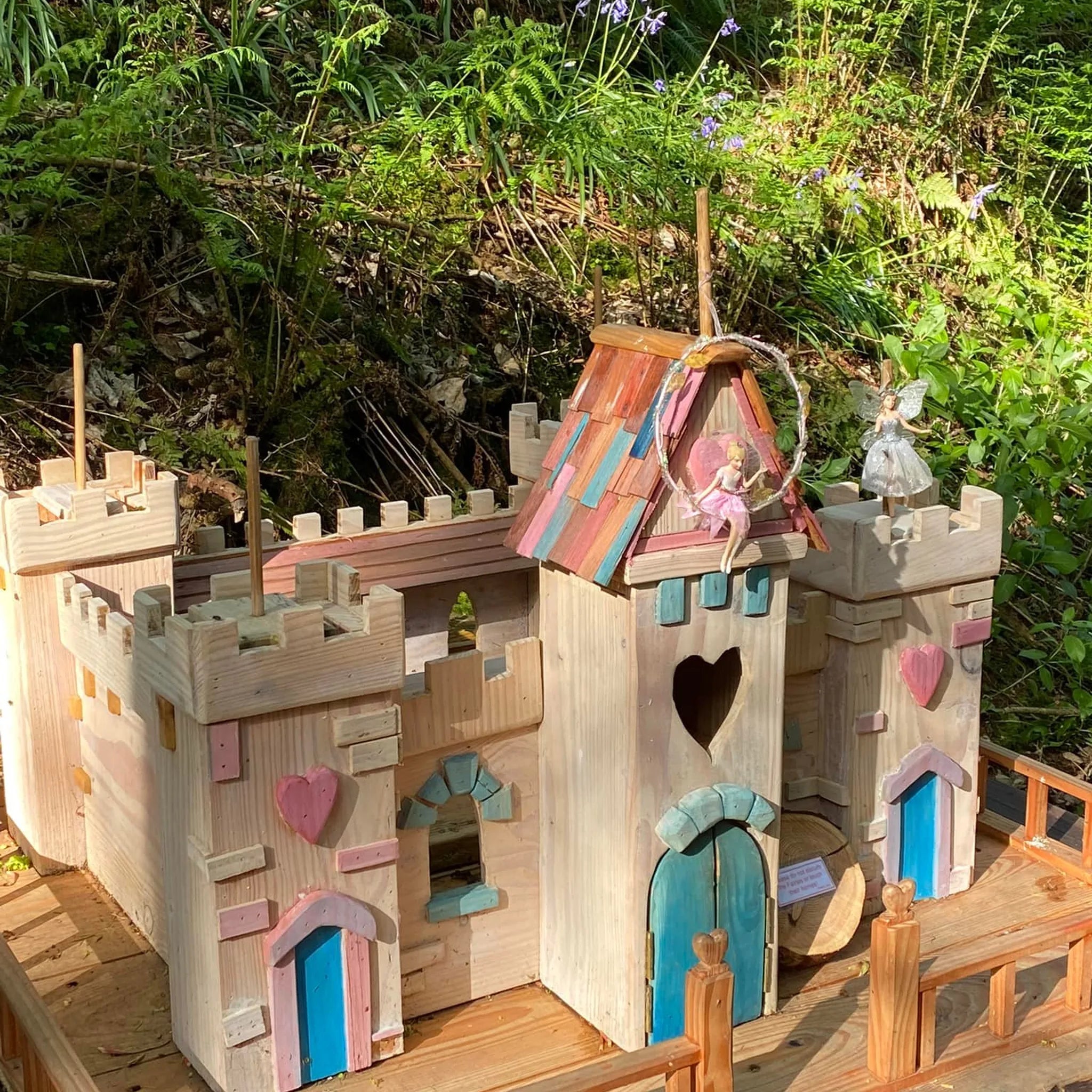 Handmade wooden fairy castle with painted stone-effect walls, multiple turrets and arched fairy windows