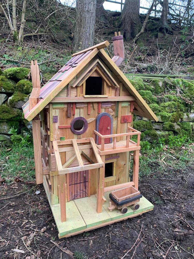 Grande maison de fées en bois avec un chariot