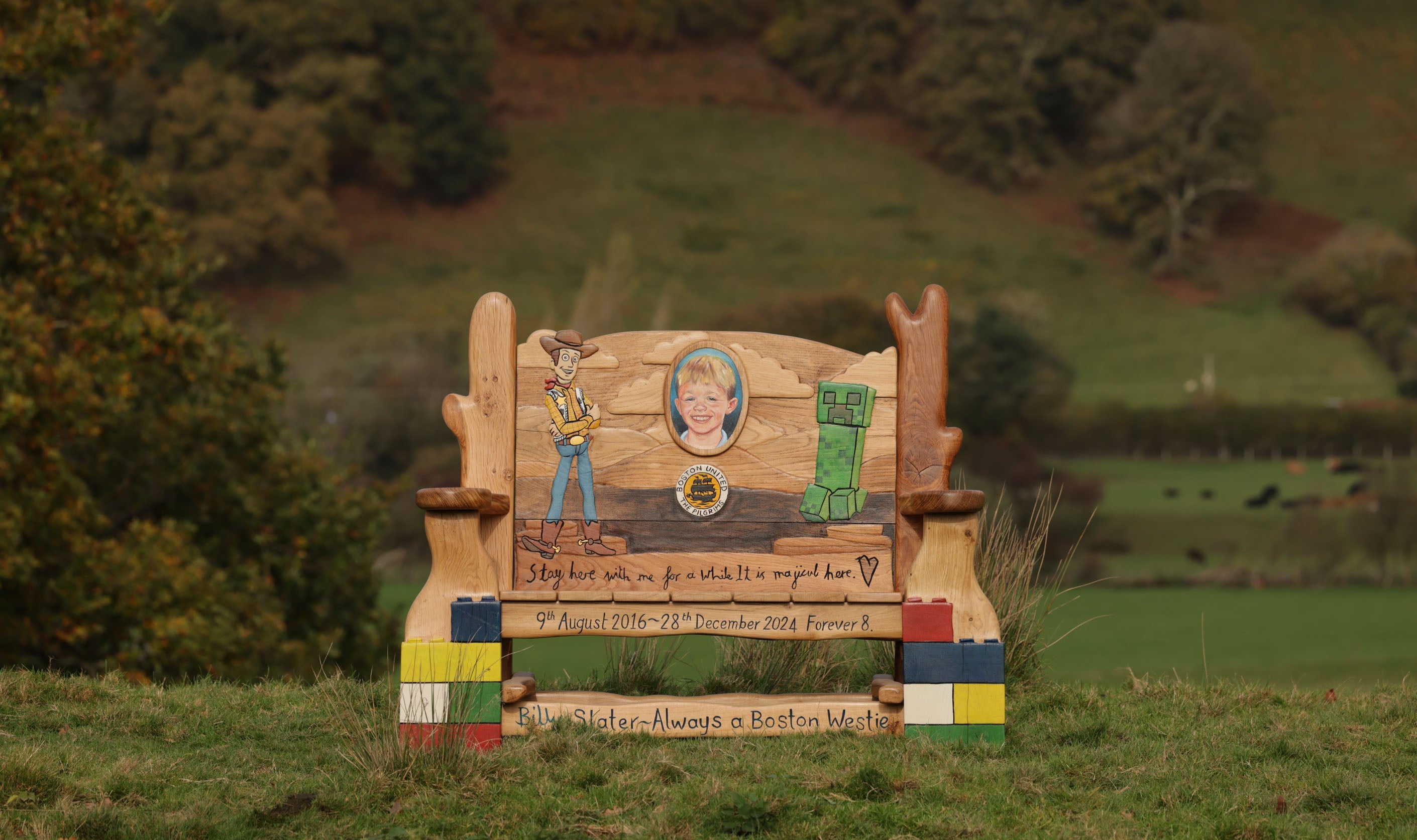 Memorial bench with engraved text and images in a field