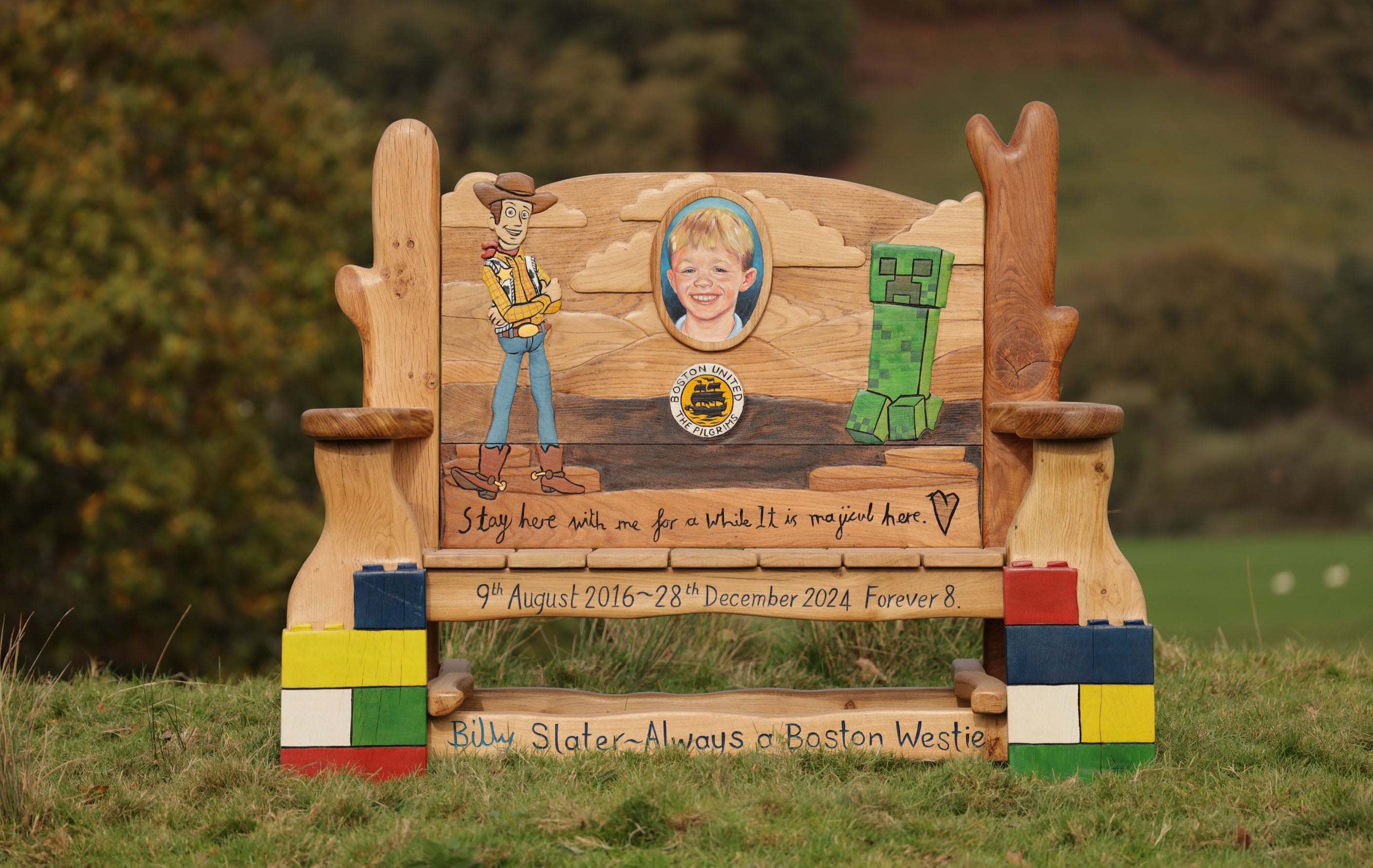 Memorial bench with illustrations and text on a grassy field