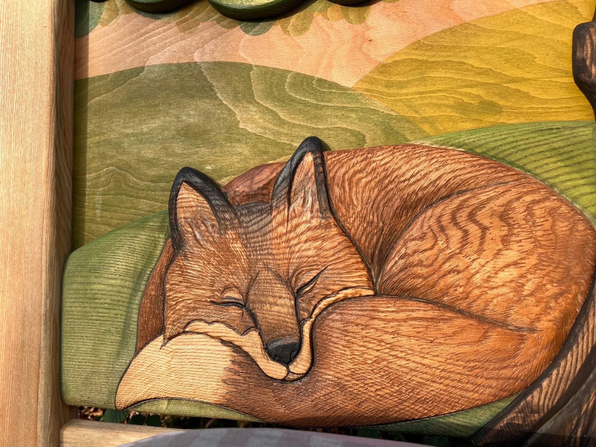 Gros plan sur un renard endormi sculpté à la main sur une tête de lit en bois, mettant en valeur les détails de l'artisanat et les tons chauds et naturels du bois. Cette sculpture complexe fait partie d'un lit d'enfant sur le thème de la nature, capturant la beauté de la faune et de la flore.