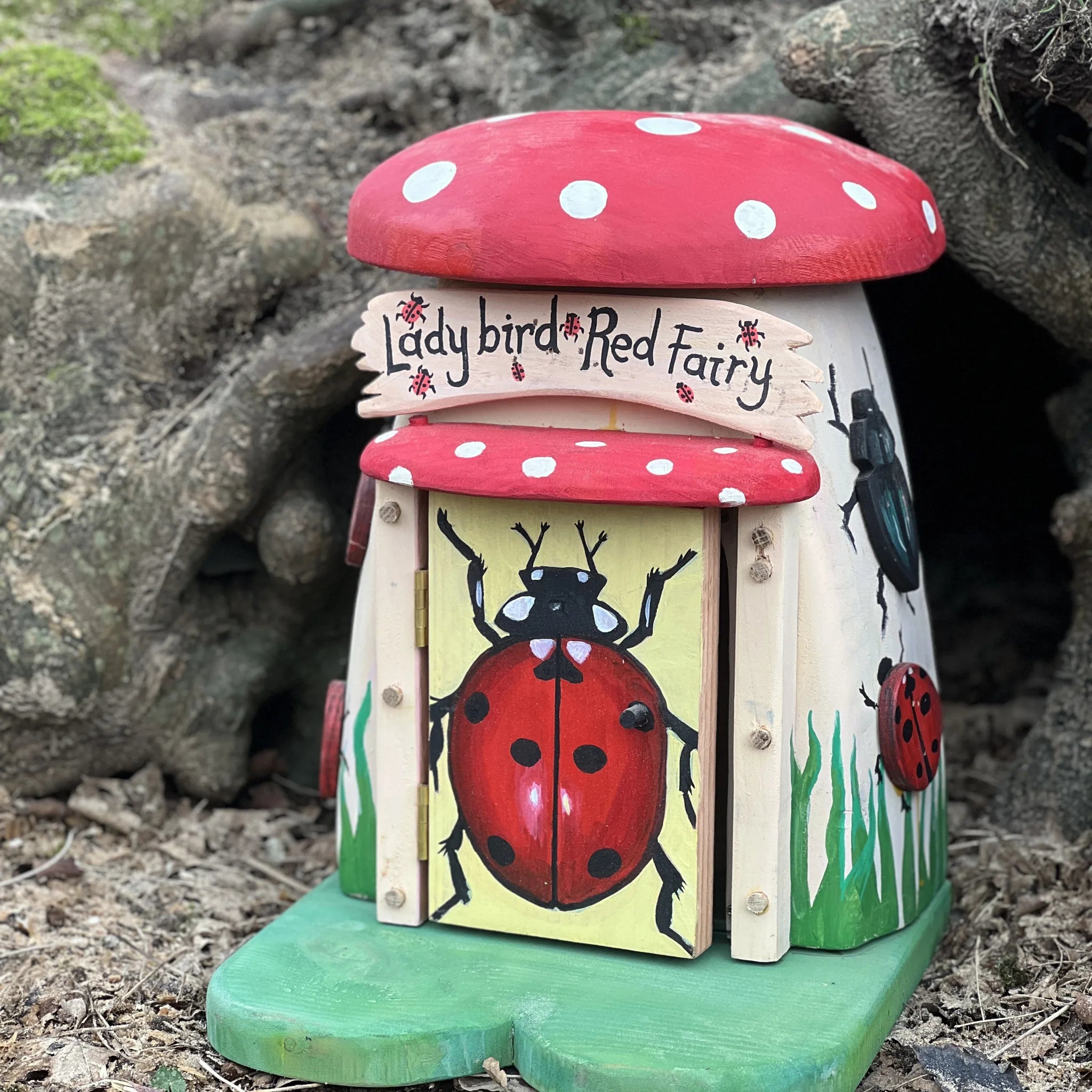 Handmade ladybird fairy house with red and black spot paintwork, toadstool-style mushroom cottage design