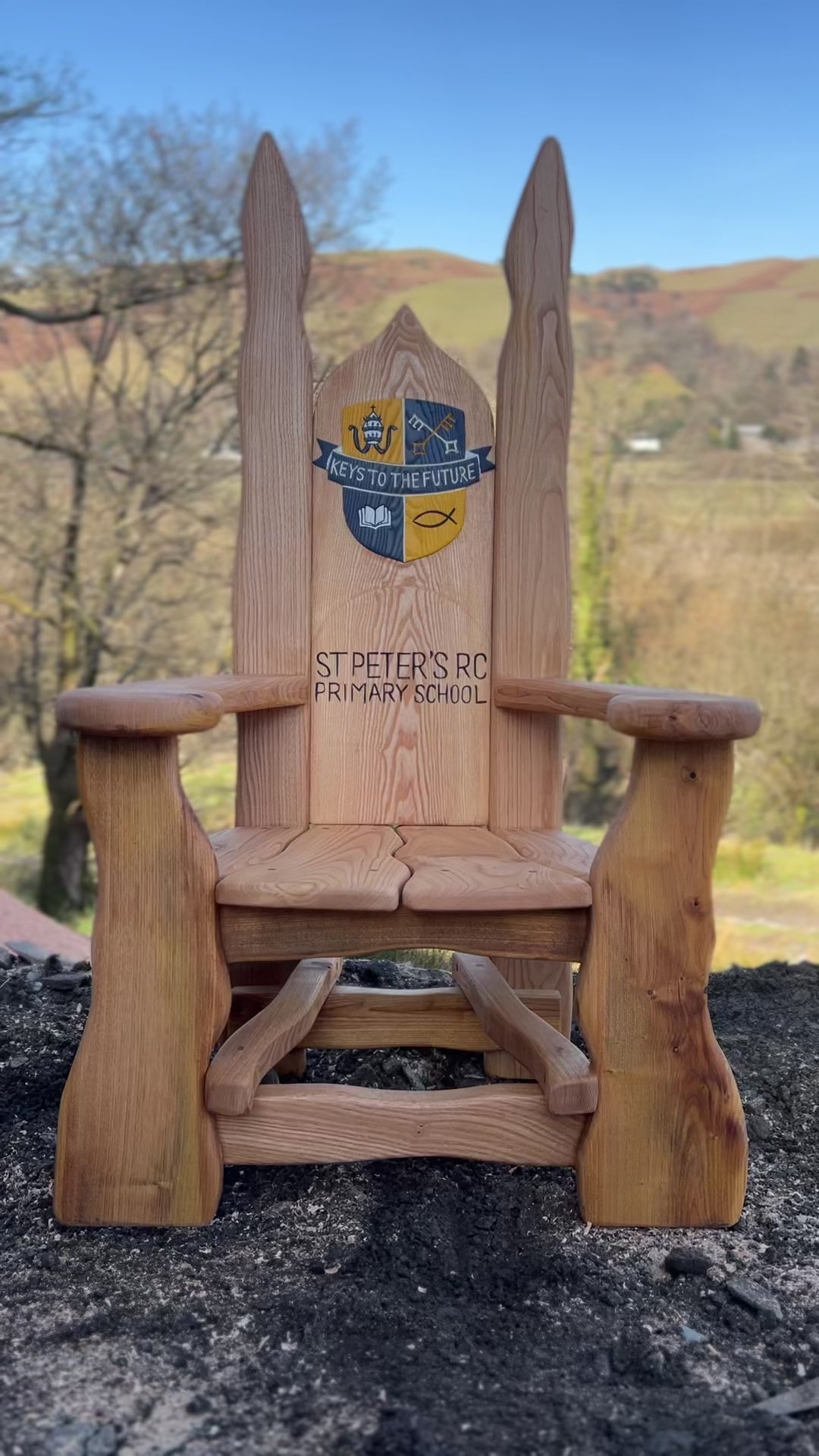 Custom oak storytelling chair featuring school logo and lettering, designed for outdoor learning spaces