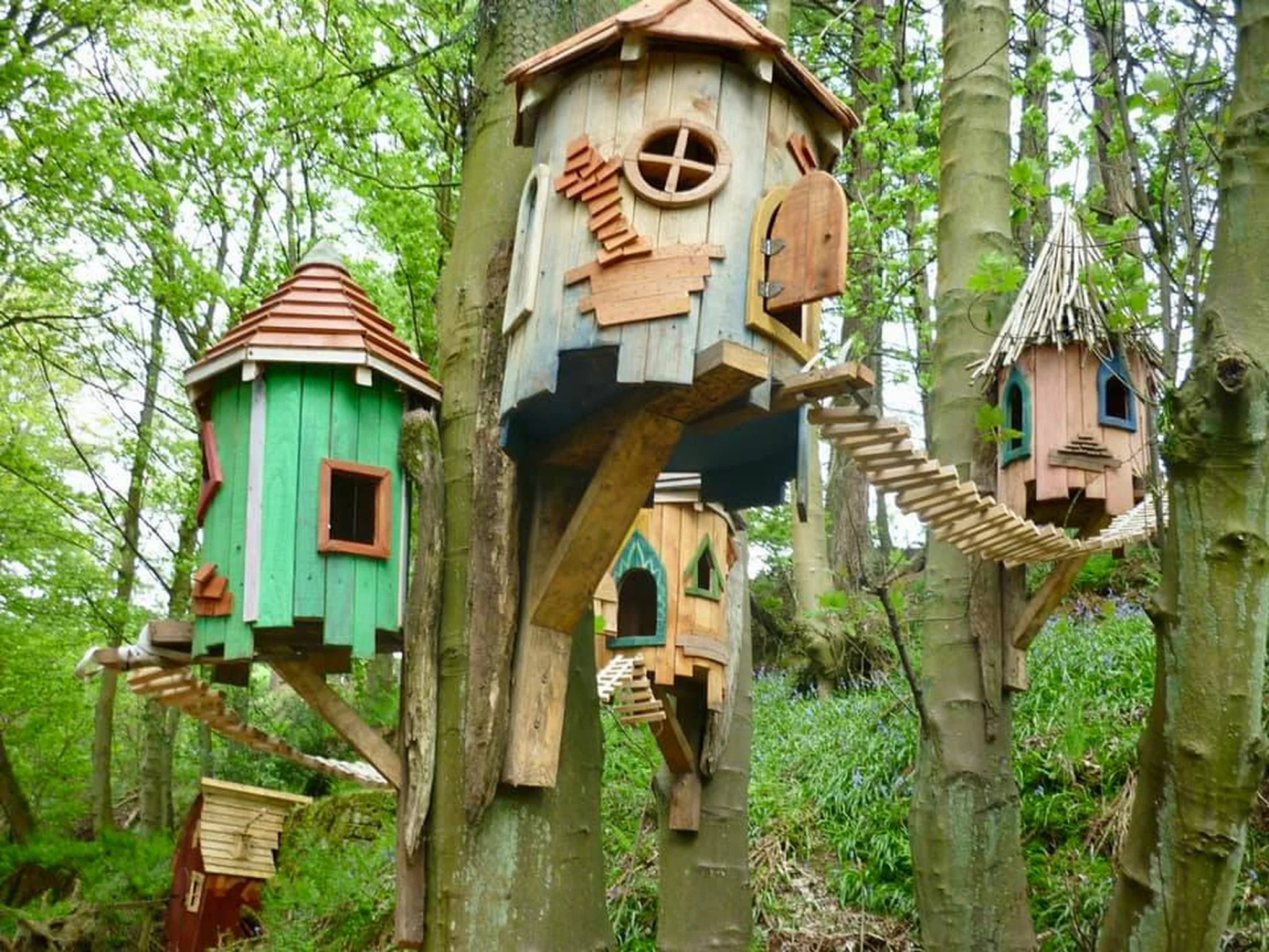 Wide side angle of woodland tree fairy cottage showing full height and natural bark branch detailing