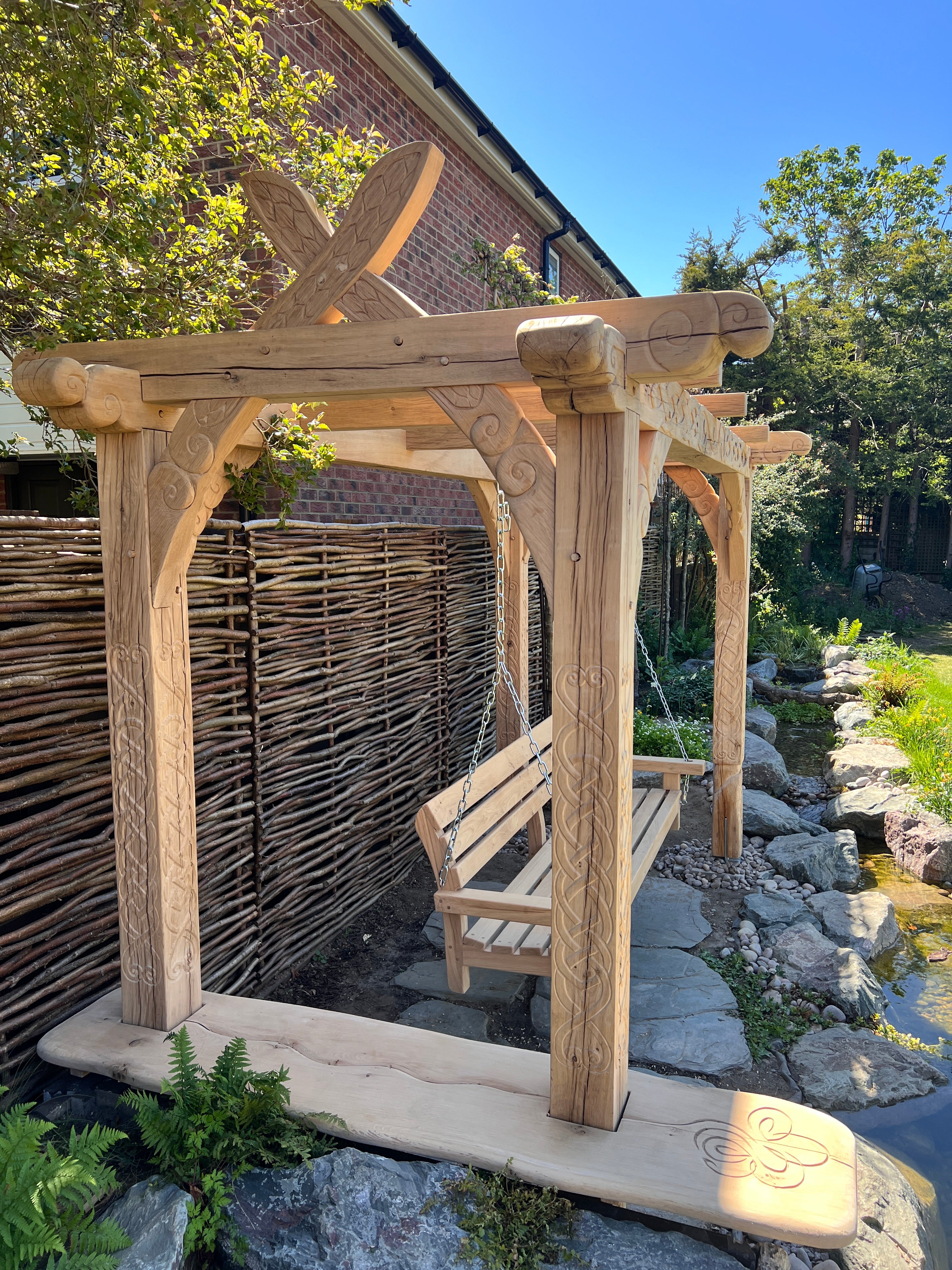 The suspended oak swing bench hanging on heavy steel chain inside the hand-carved Viking garden arbour