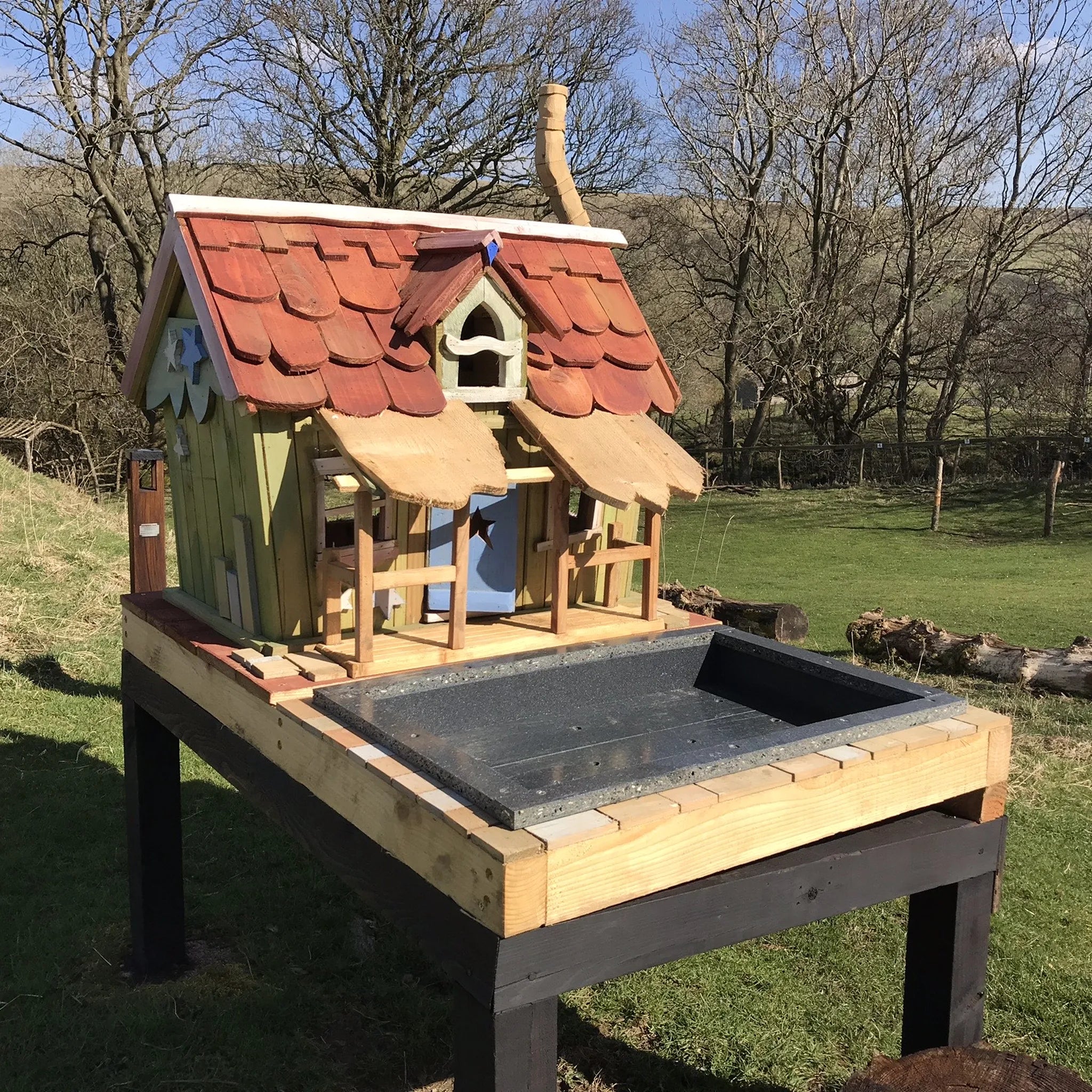 Handmade fairy wishing cottage with red-painted roof, working-style wishing well and hand-painted details