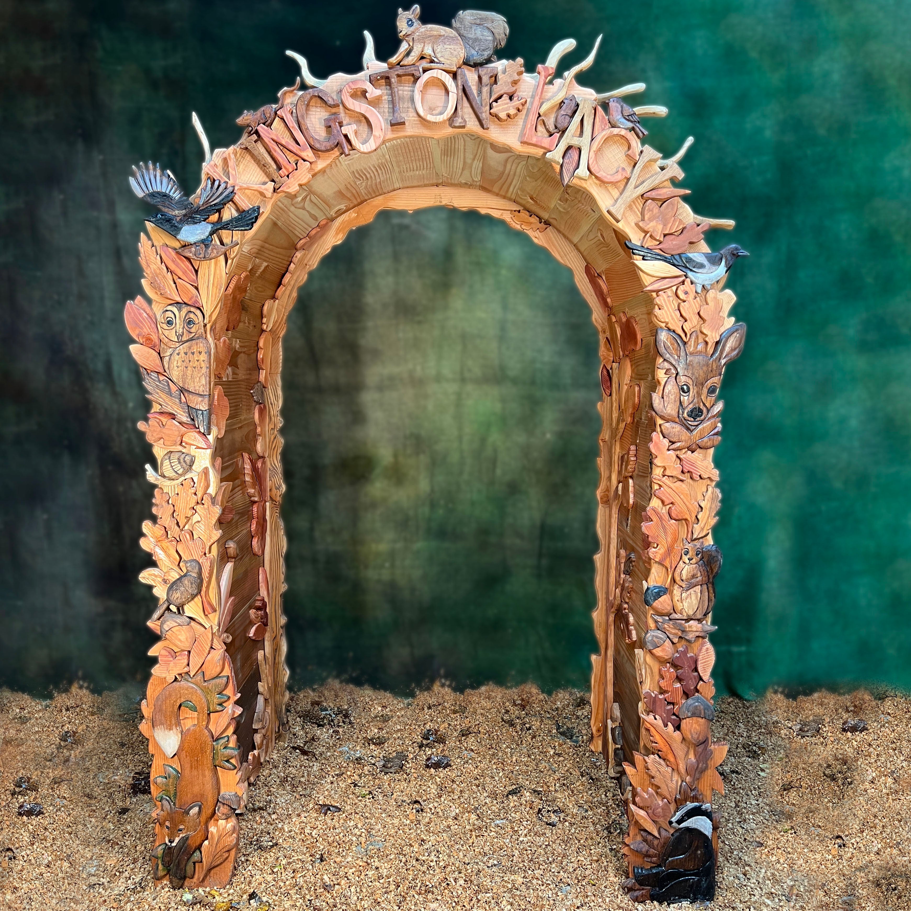 front view of fantasy carved wooden arch with woodland animals owls birds fox and leaves