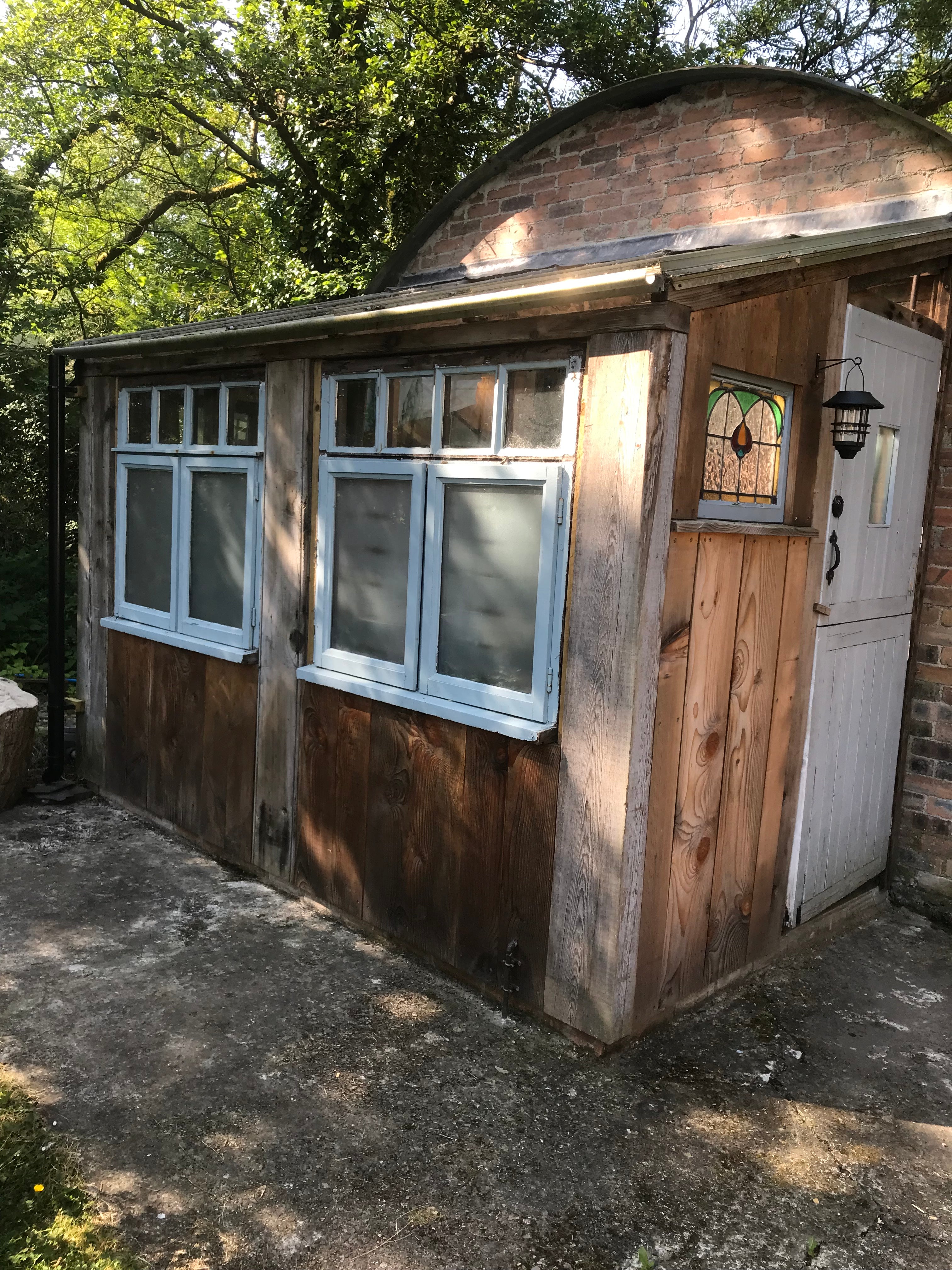 Rustic wooden compost toilet in Ireland with a stained-glass window and eco-friendly design