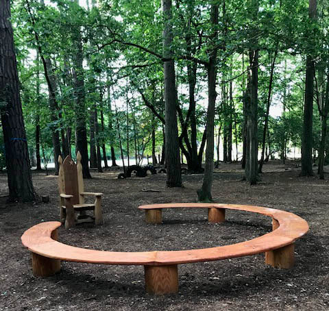 forest school reading chair in woodland surrounded by circular bench