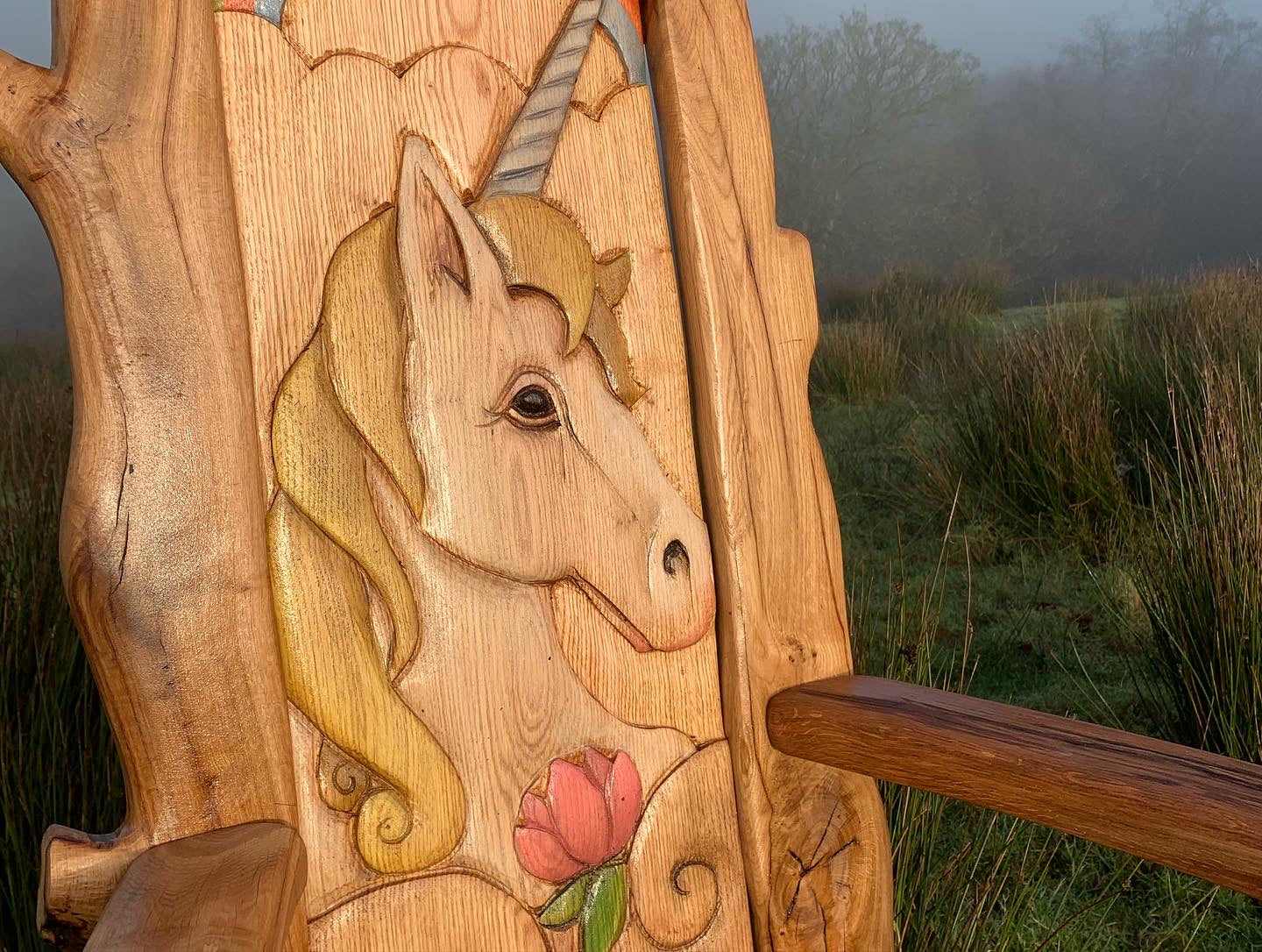 Unicorn carving on wooden bench in misty field