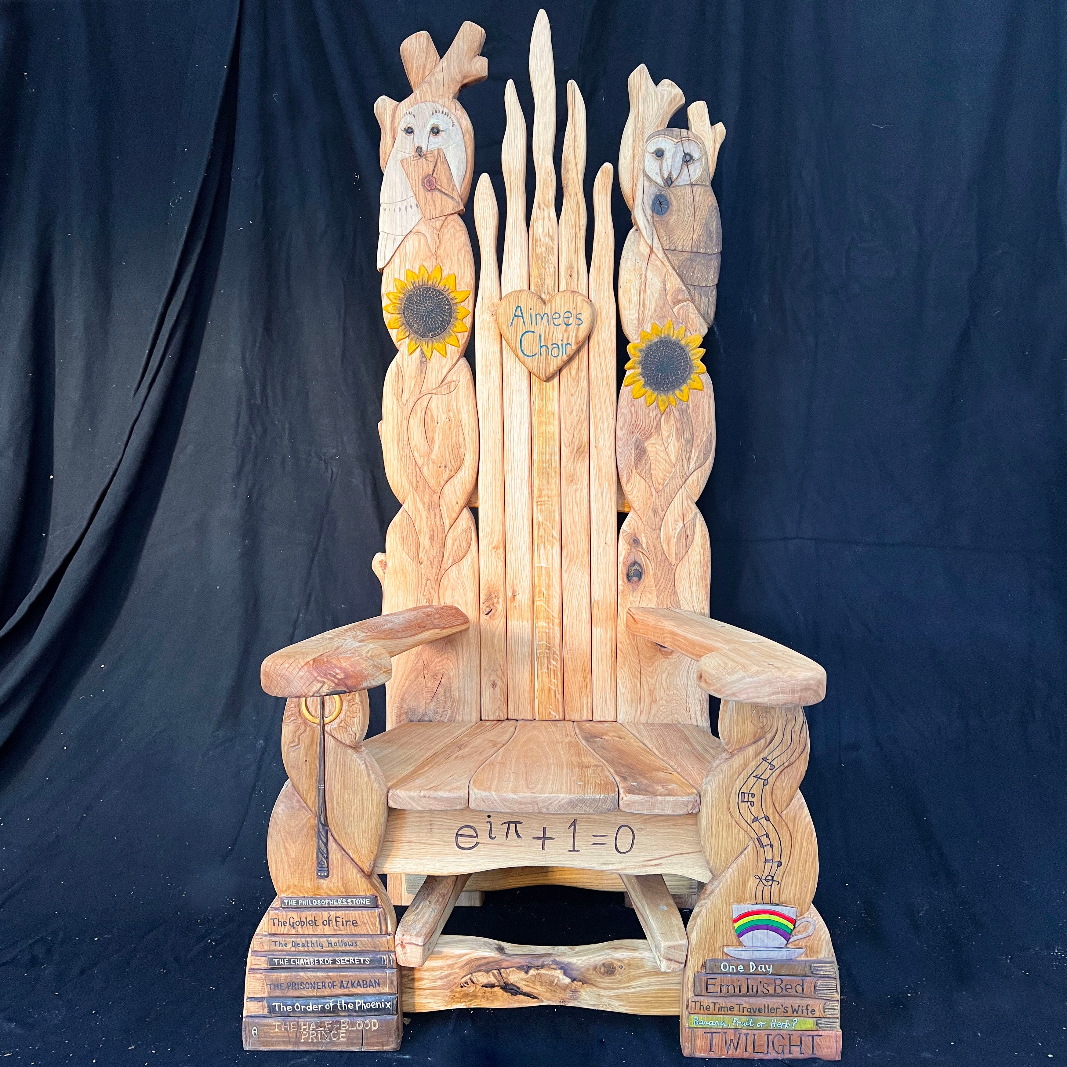 Handcrafted wooden storytelling throne chair featuring intricate carvings of owls, sunflowers, and engraved book spines, made from sustainable British oak