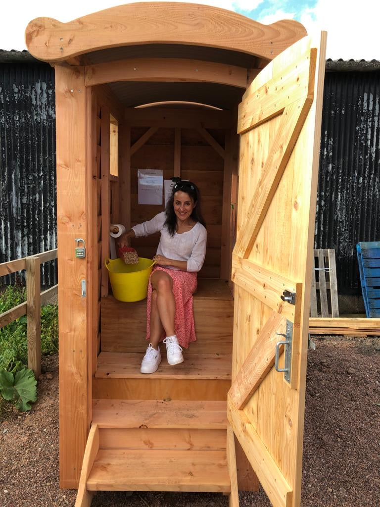 Timber compost toilet in school garden with teacher inside