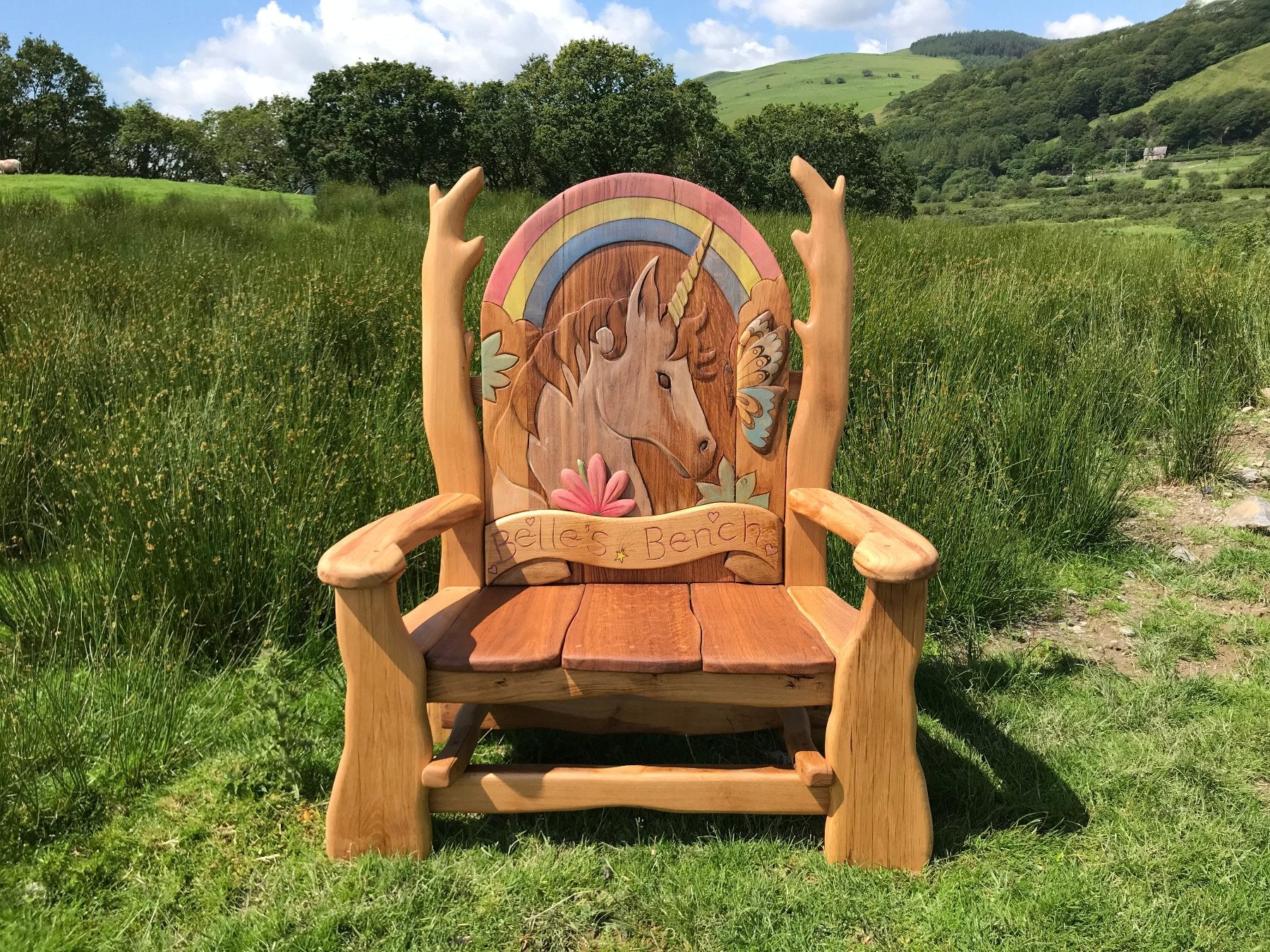 Handcrafted wooden memorial bench with intricate carvings, surrounded by a lush green garden, symbolizing remembrance and love