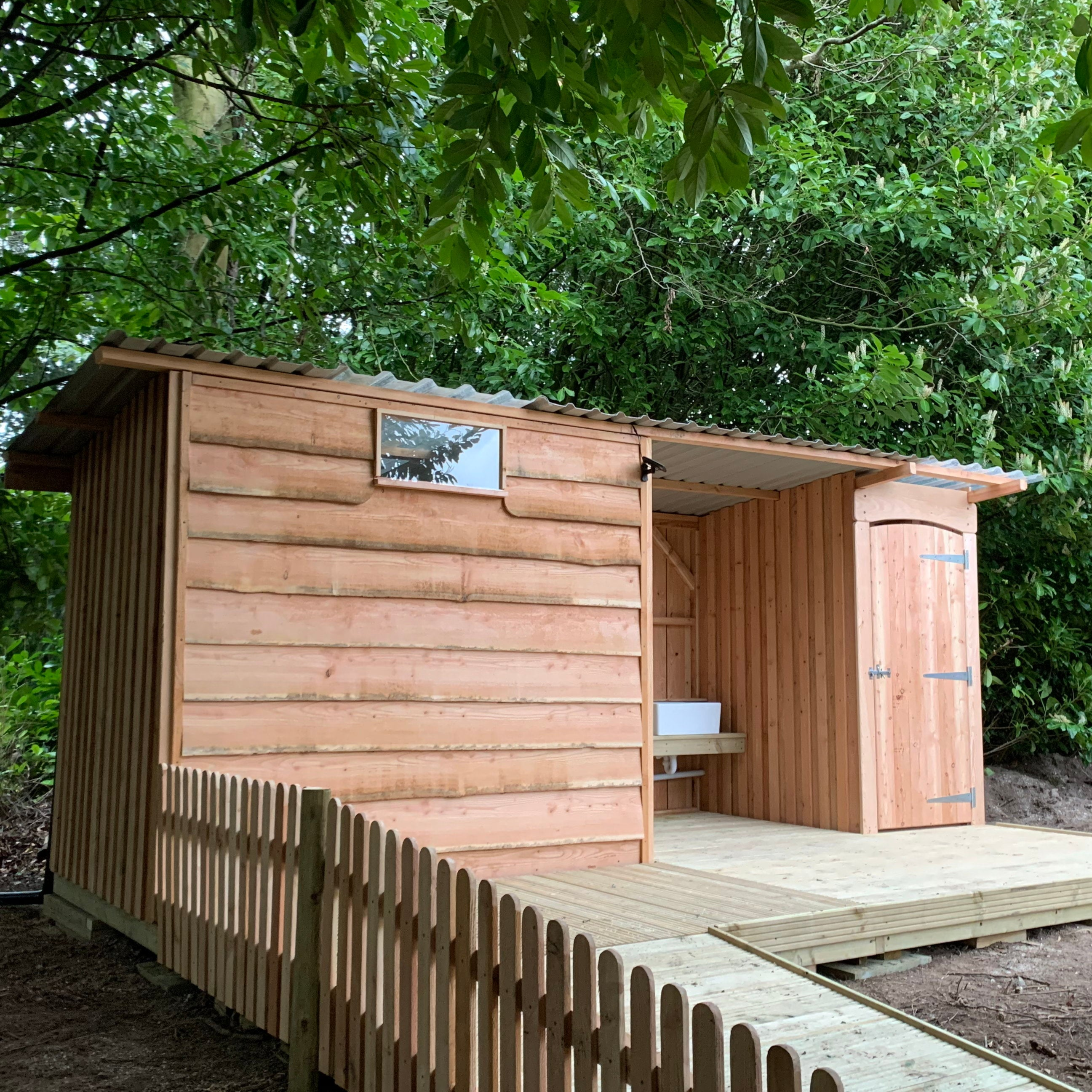 Composting Toilet with Disabled Access featuring a wheelchair ramp and locally sourced timber design, set in a natural outdoor setting