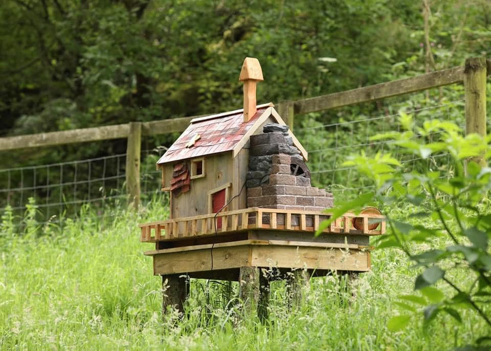 Rustic fairy house with a chimney in a grassy area