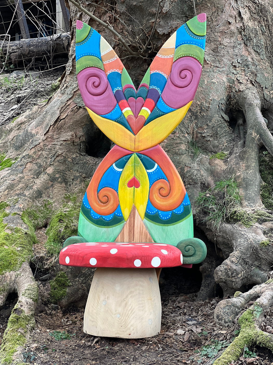 Chaise de fée colorée avec ailes de papillon près des racines d'un arbre