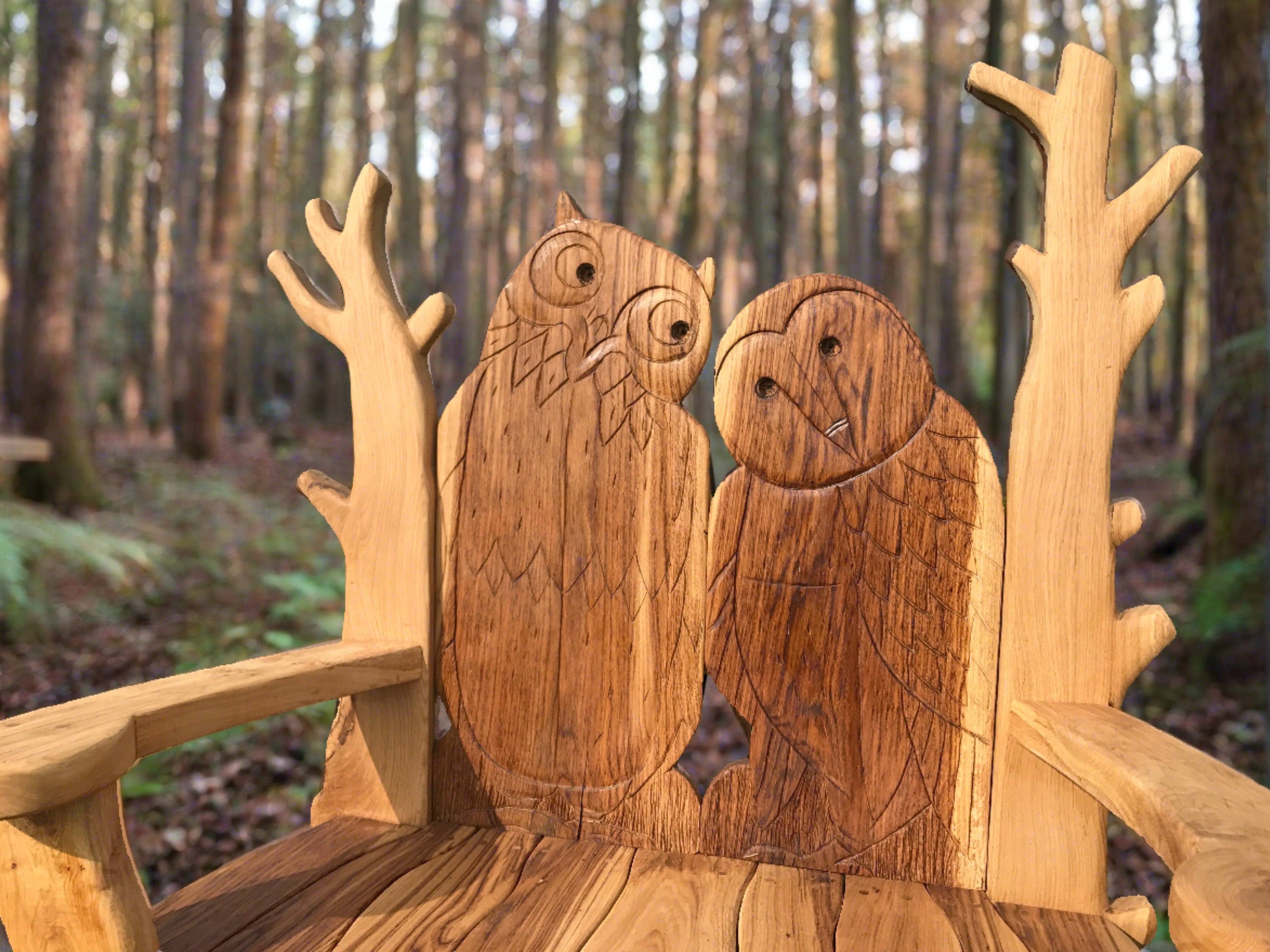 Close-up of owl carvings on a wooden bench in the forest.