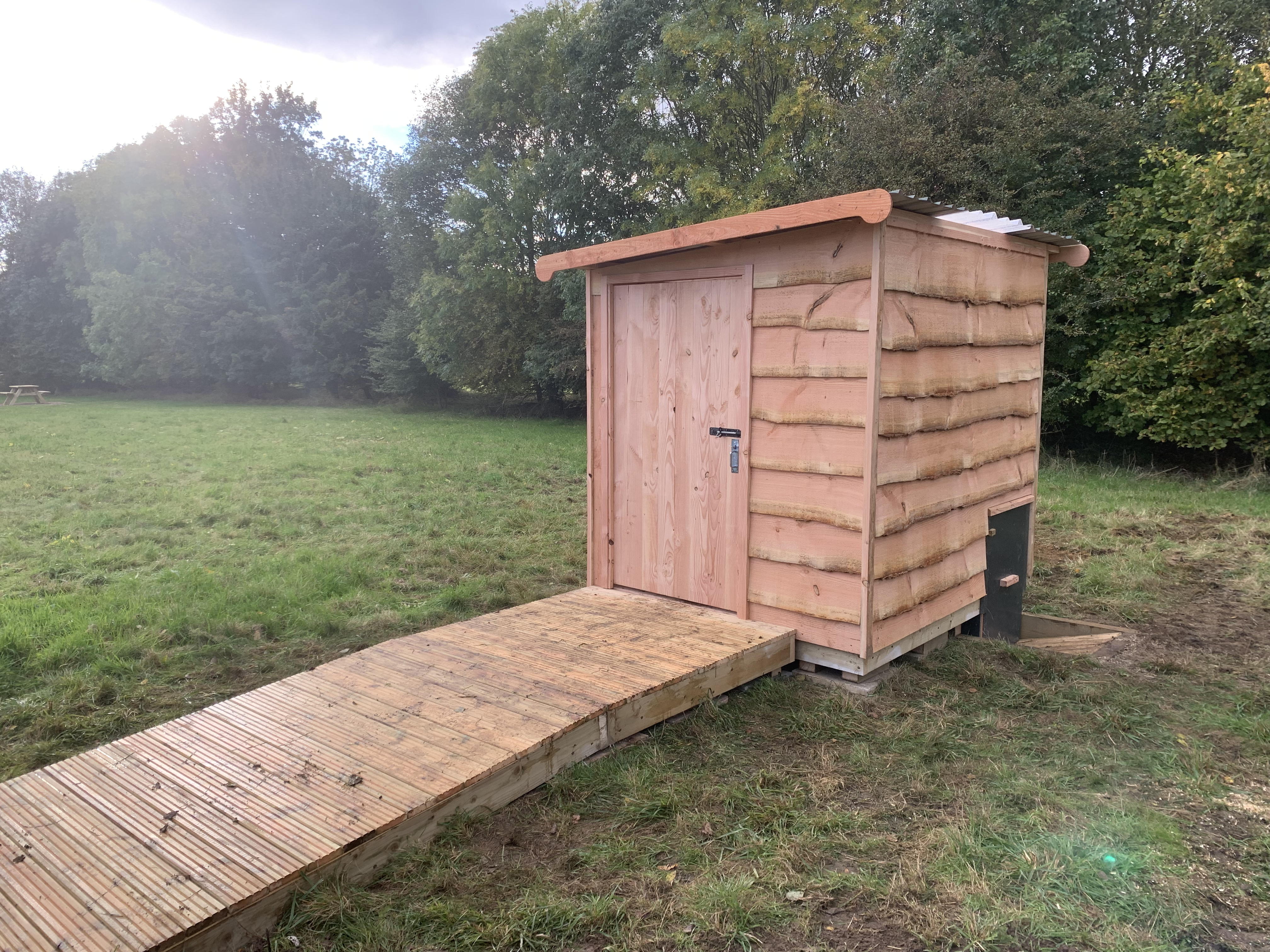 Compost toilet with ramp in grassy field