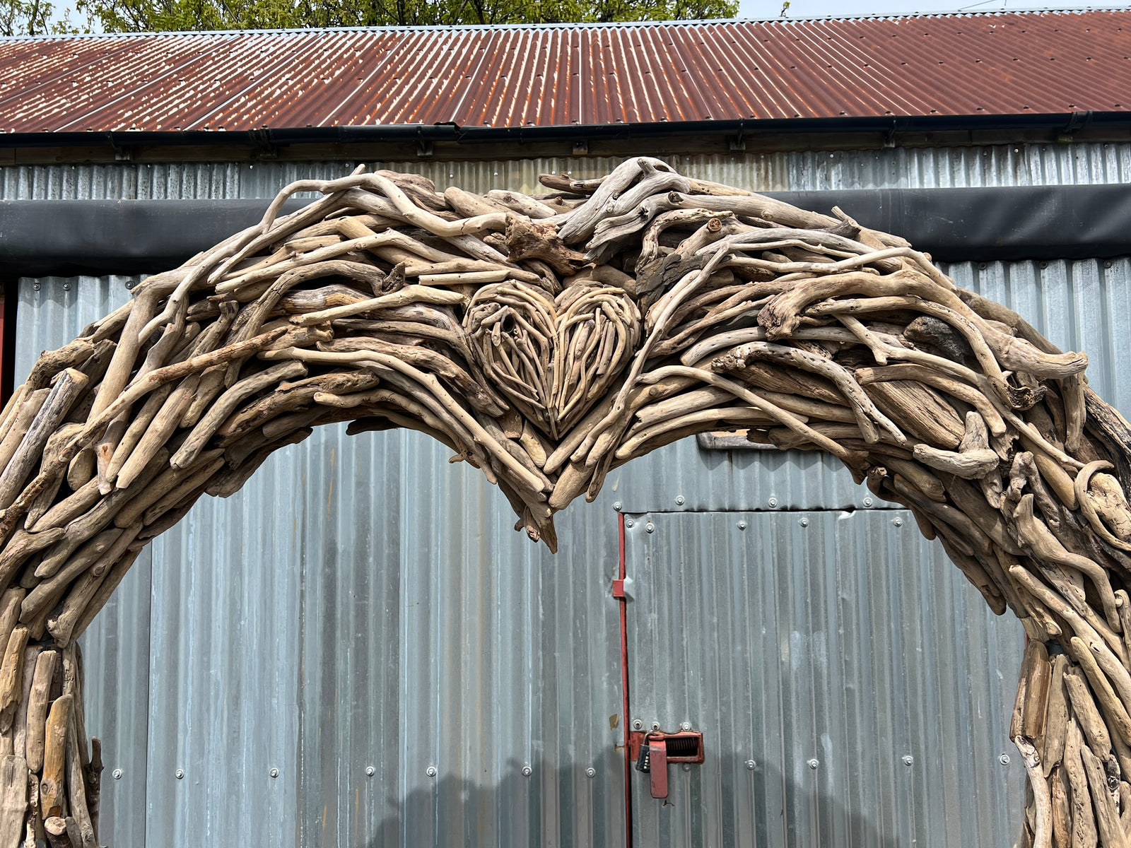 Driftwood wedding arch with flowing branch canopy in outdoor setting — bespoke wooden arch, Mid Wales