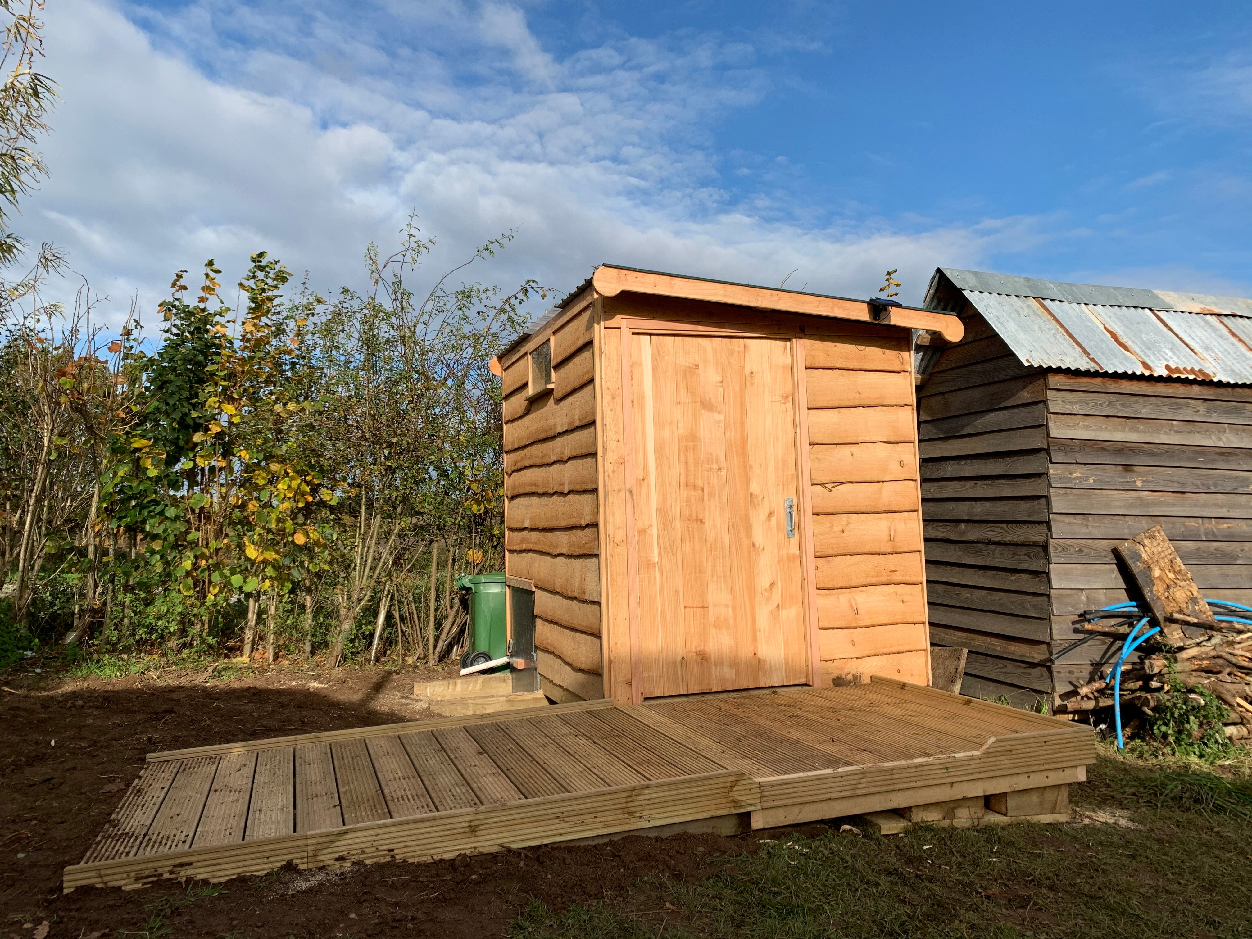 Wooden compost toilet with ramp in rural setting