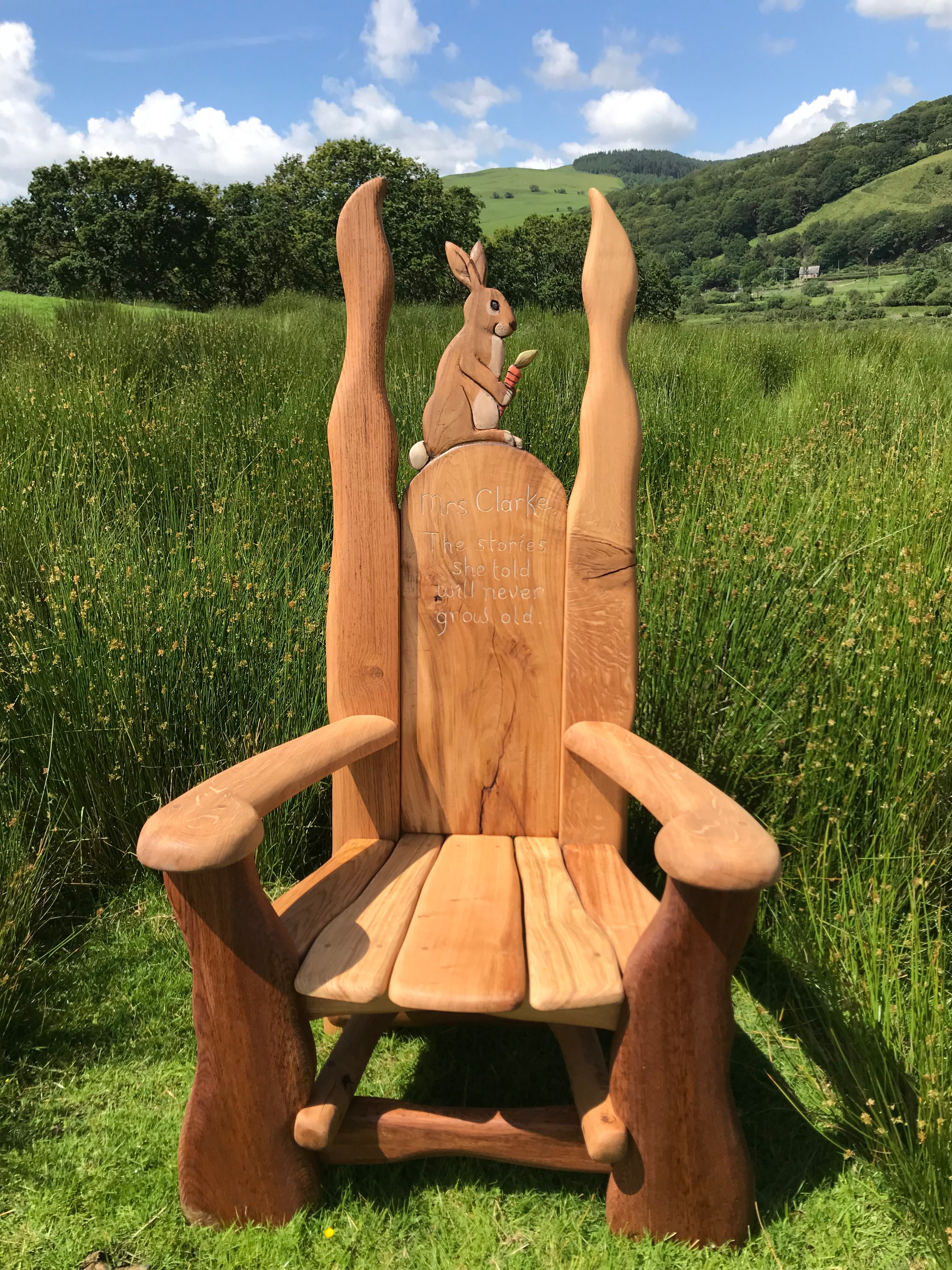 Rabbit reading chair in a green field with scenic backdrop