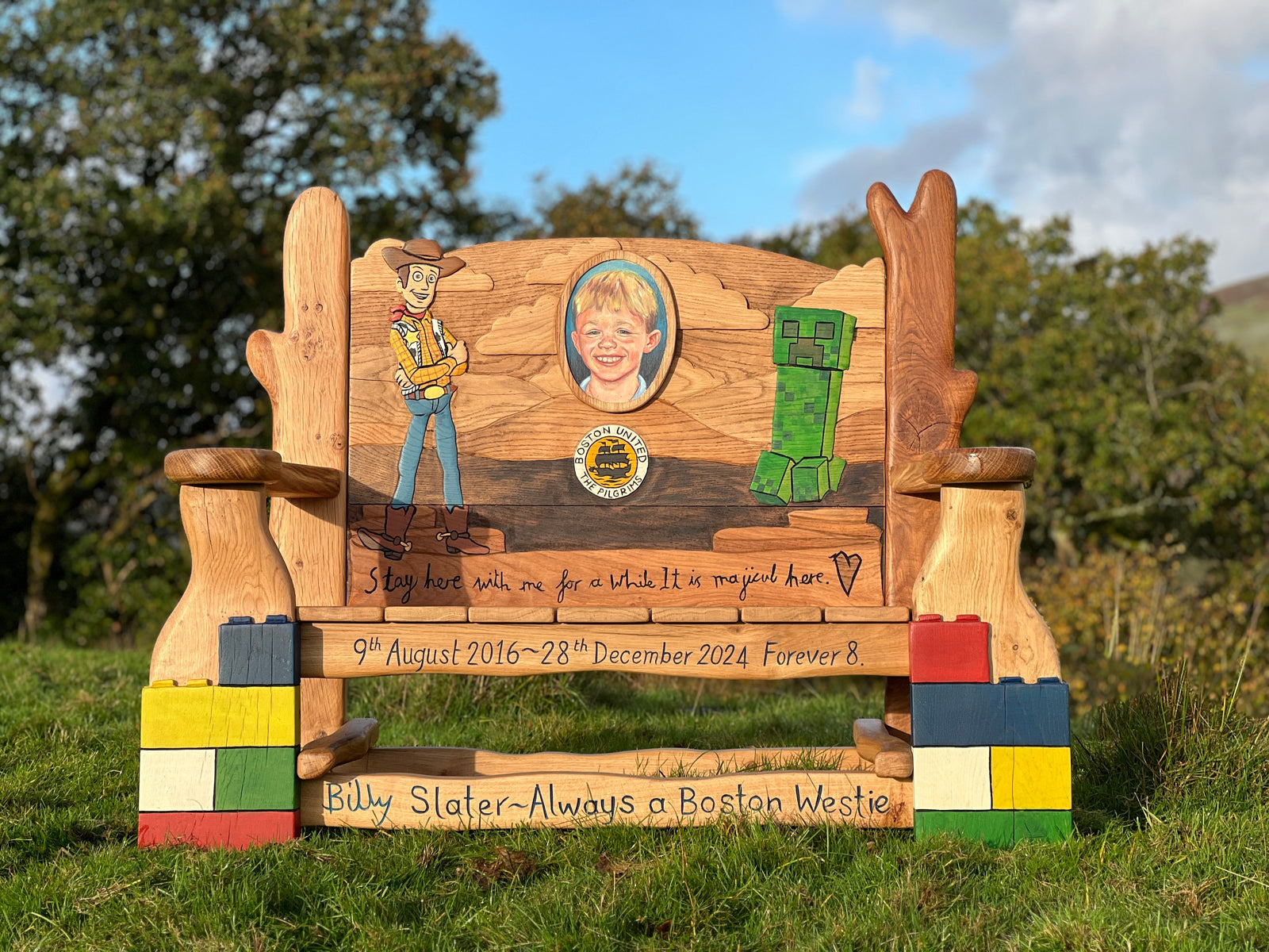 Wooden bench with engraved images and text in an outdoor setting