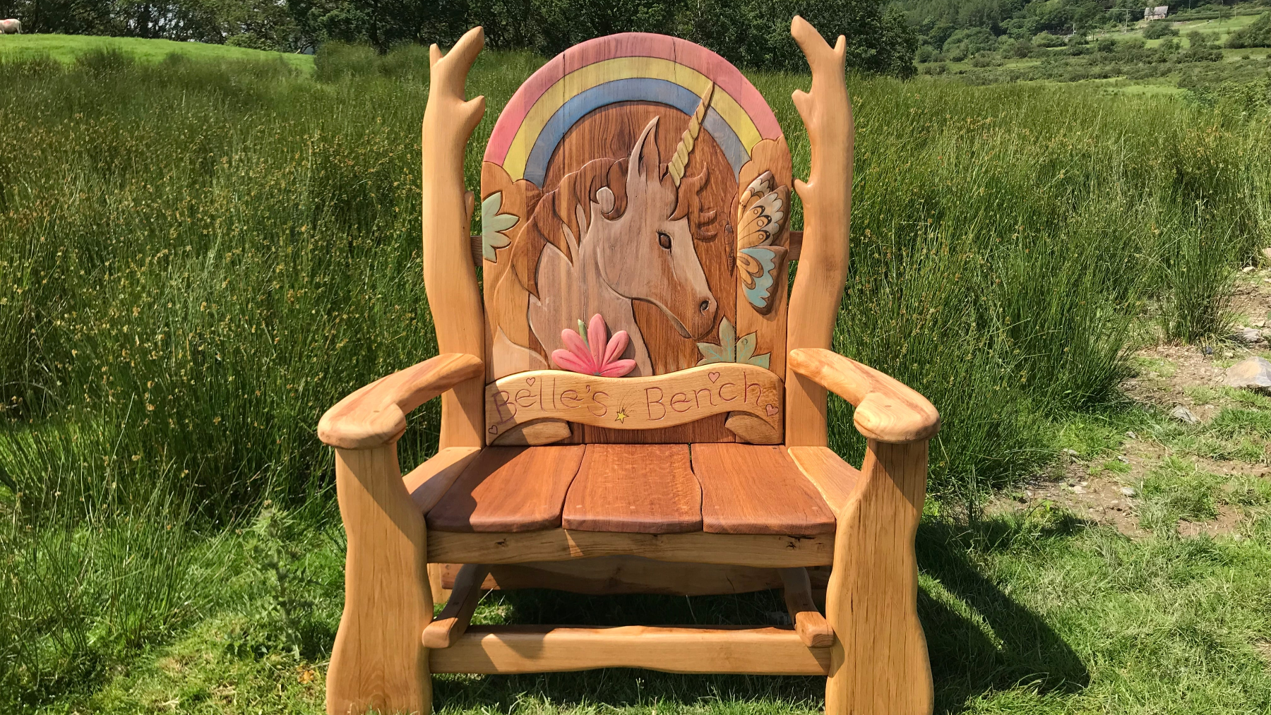 Handcrafted wooden memorial bench with intricate carvings, surrounded by a lush green garden, symbolizing remembrance and love