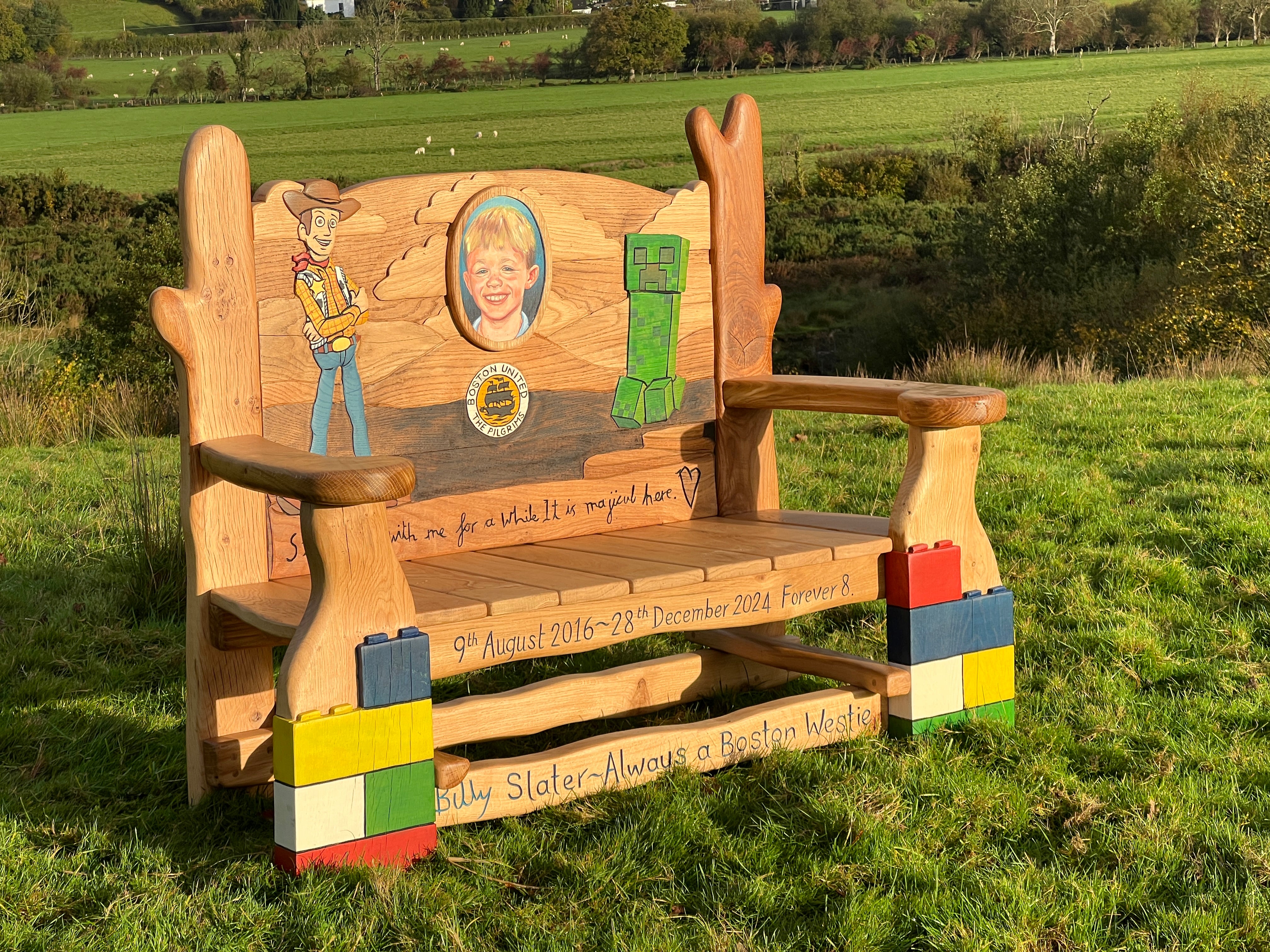 Wooden memorial bench with colorful base in a grassy field