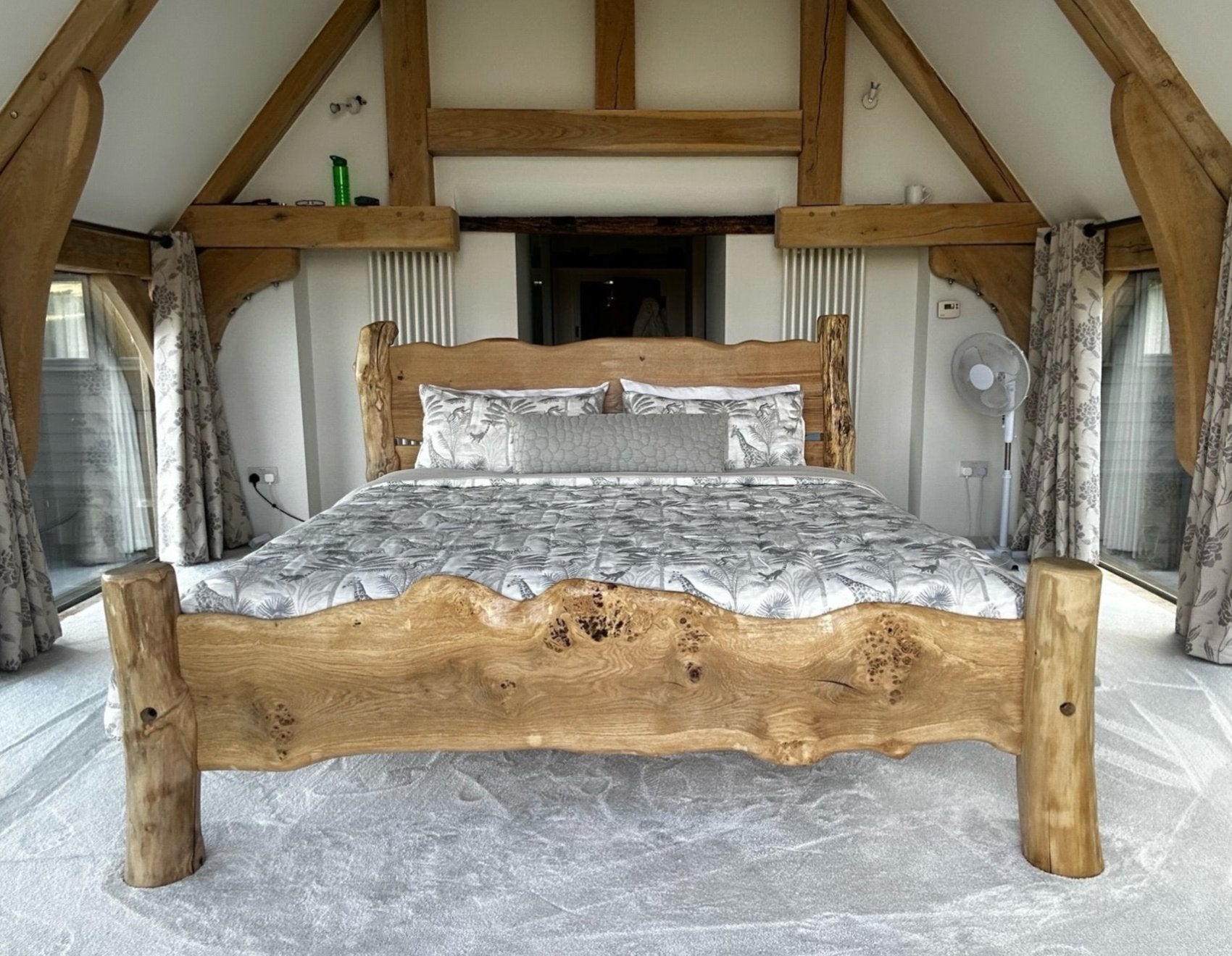 Handcrafted rustic wooden bed with natural wood grain details, set in a cozy loft bedroom with exposed timber beams and soft, elegant bedding