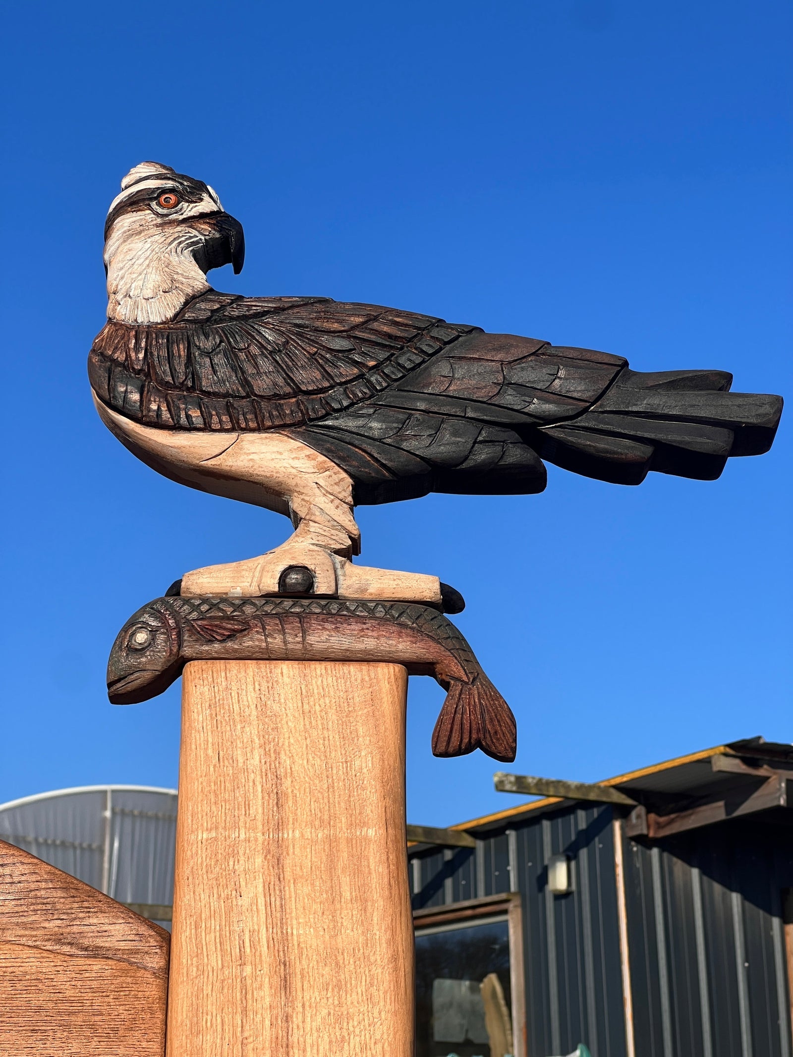 Close-up detail of the carved osprey with spread wings and carved landscape on the bench