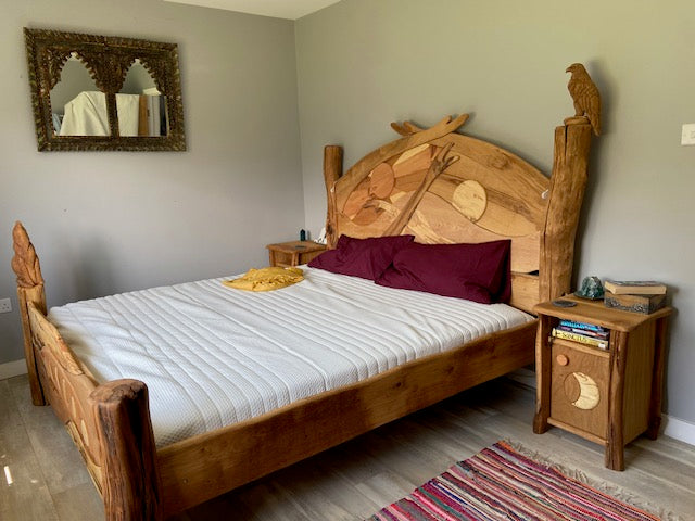 Seitenansicht eines maßgefertigten Holzbettes mit einem Kopfteil im Sonnenaufgangsdesign, ergänzt durch passende Nachttische