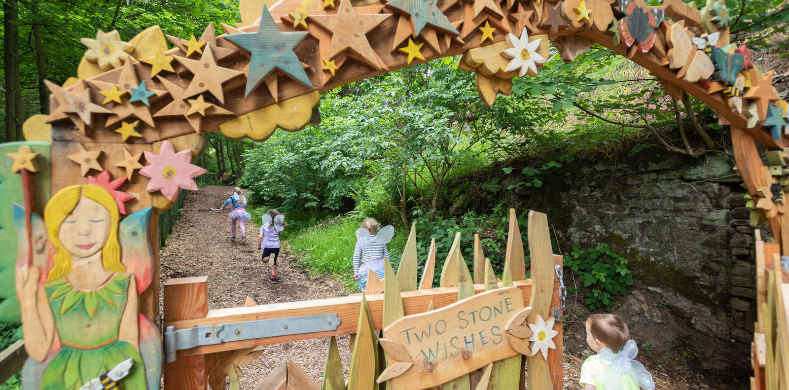 Wooden fairy-themed archway with star decorations in a forest setting