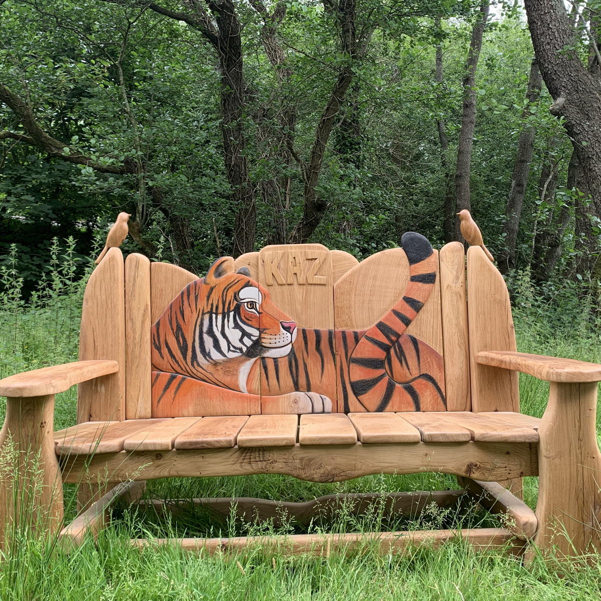 Holzbank mit geschnitztem Tigermotiv in einer Waldlandschaft